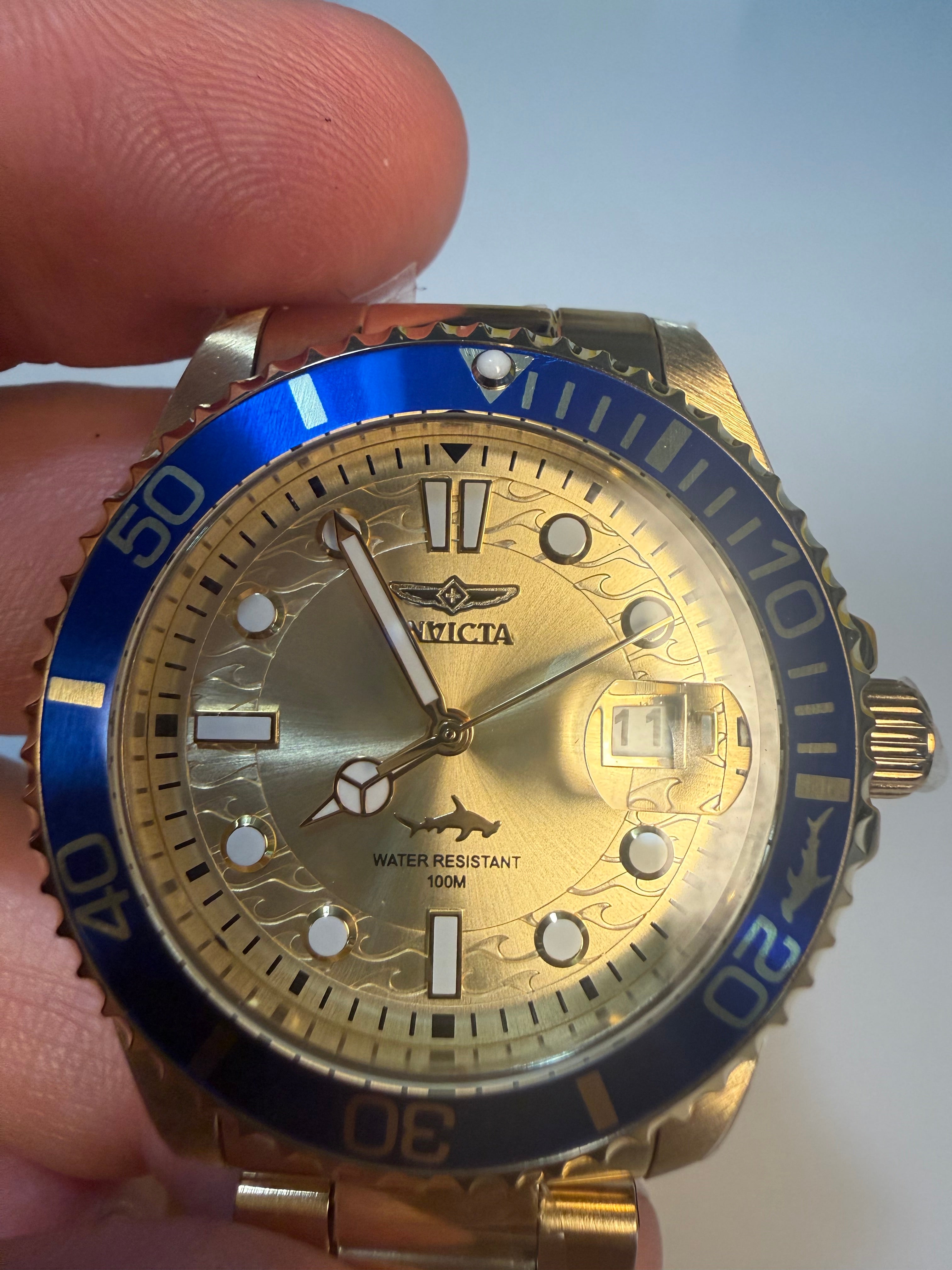 Invicta 38mm Unisex Pro Diver Gold and blue wristwatch held in a hand against a light background
