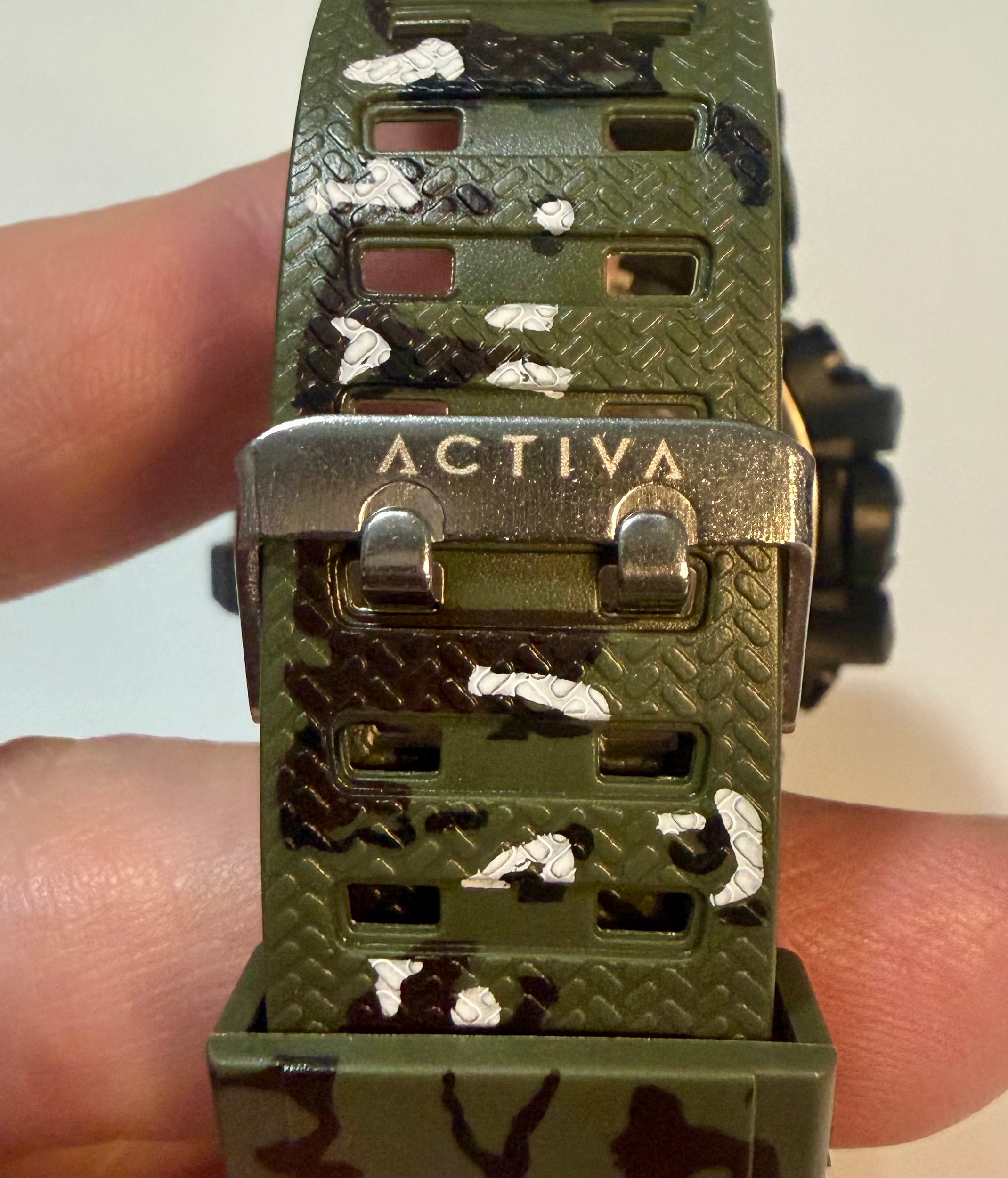 Activa Tactical X Green watch with 'Activa' branding held between fingers on a white background