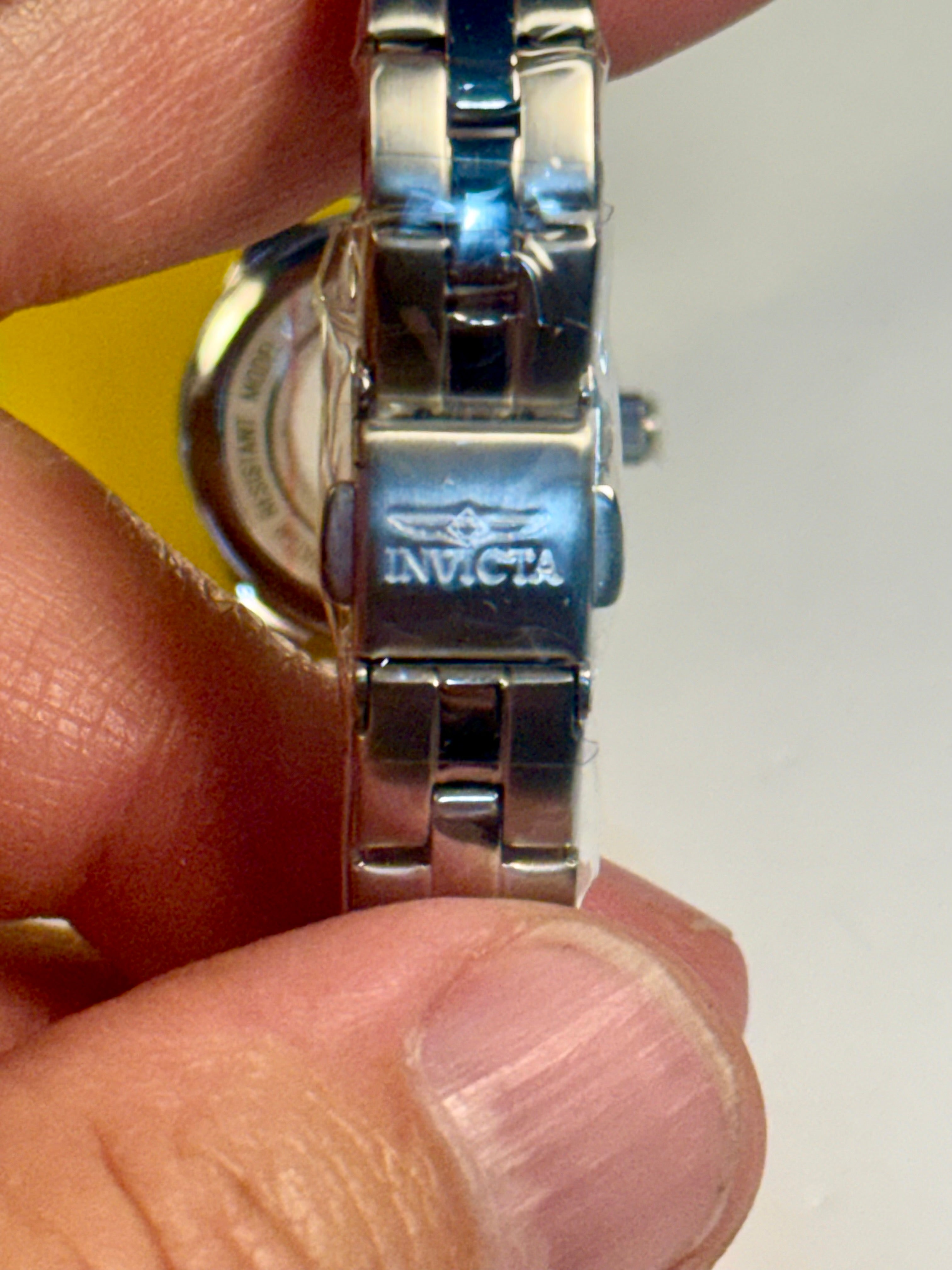 Invicta Ladies Ocean Voyage Silver Invicta watch band held between fingers with a white background