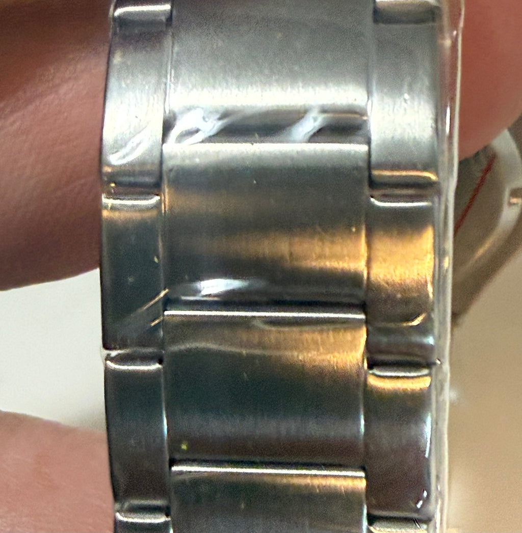 Close-up of a silver metal watch band on a wrist.