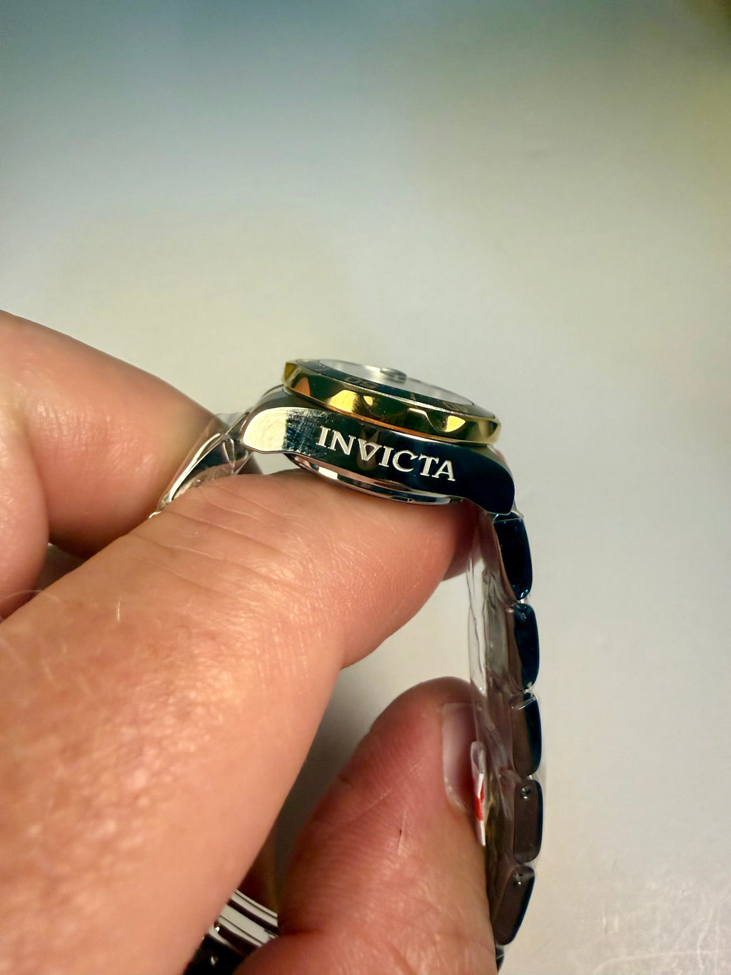 Hand holding a Ladies Invicta Pro Diver 24.5 mm watch with 'Invicta' branding on a plain background