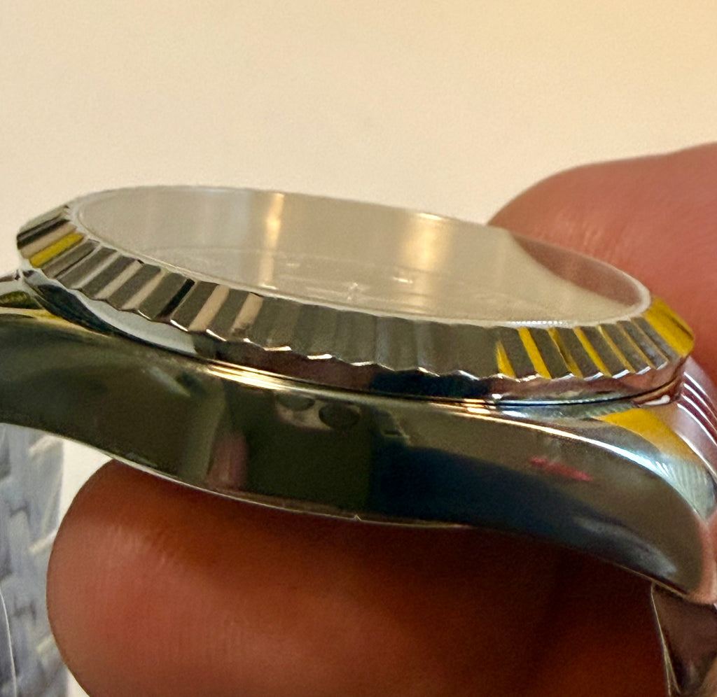 Close-up of a Ladies Specialty Windsor 36mm silver watch case held between fingers
