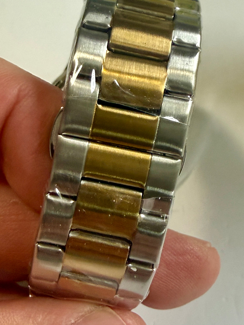 Close-up of a Invicta Specialty I Mens 42mm silver and gold watch band on a person's wrist.