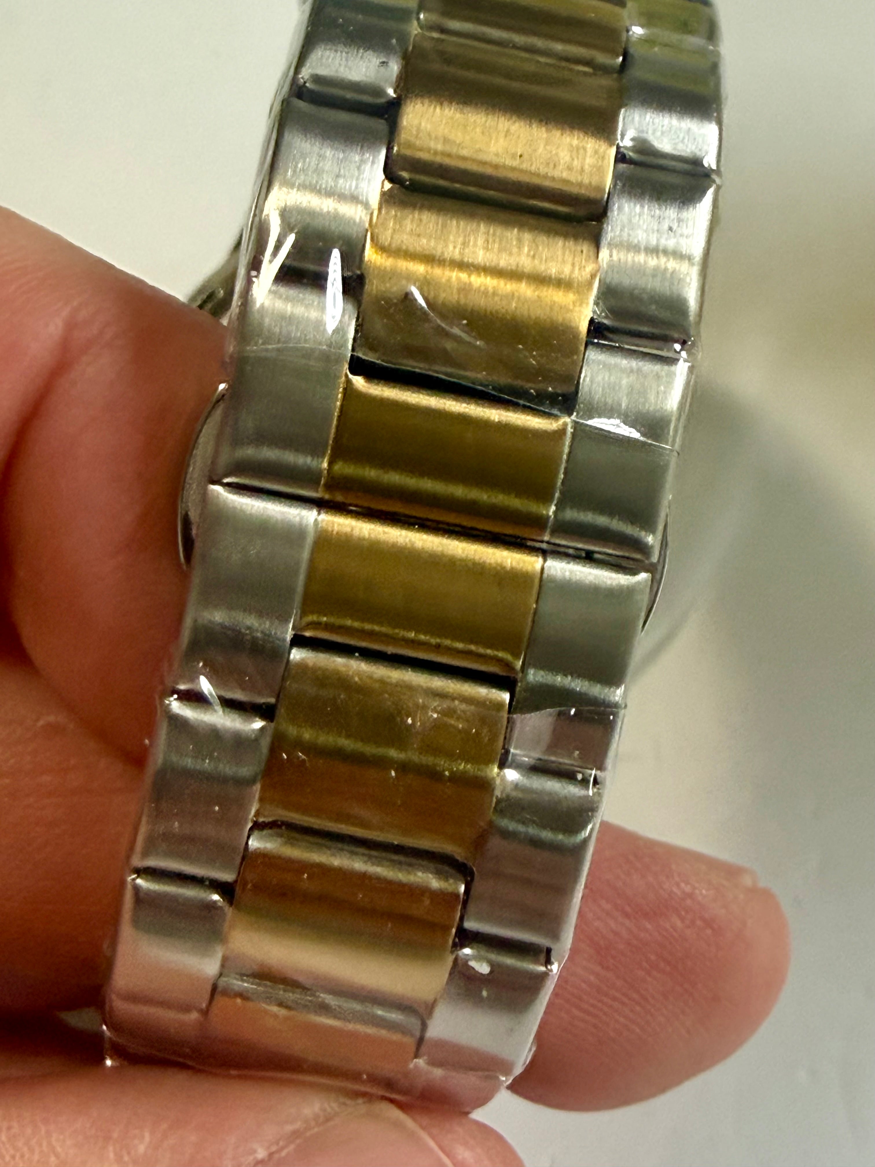 Close-up of a Invicta Specialty I Mens 42mm silver and gold watch band on a person's wrist.