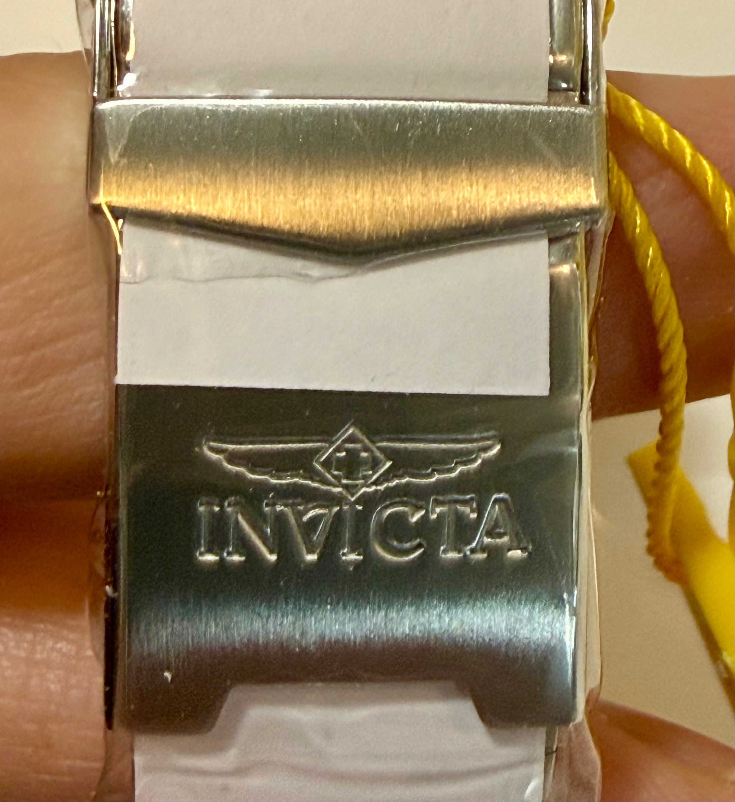 Close-up of a silver Invicta watch buckle on a wrist.