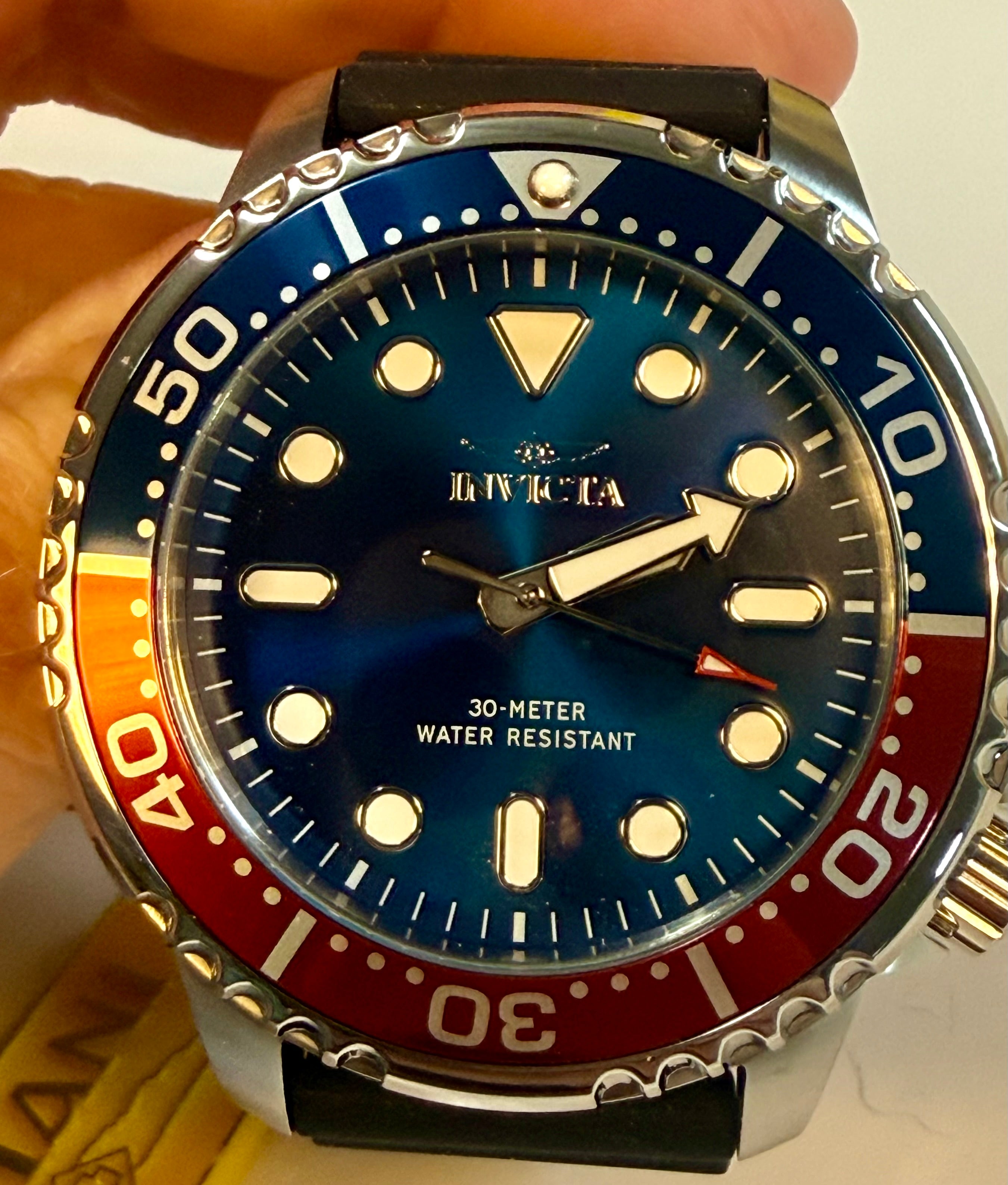 Invicta Mens Pro Diver 48mm Silicone band Watch with blue face and red and orange bezel held by a hand