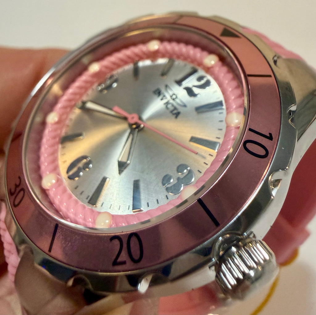 Pink wristwatch with silver case held by a hand