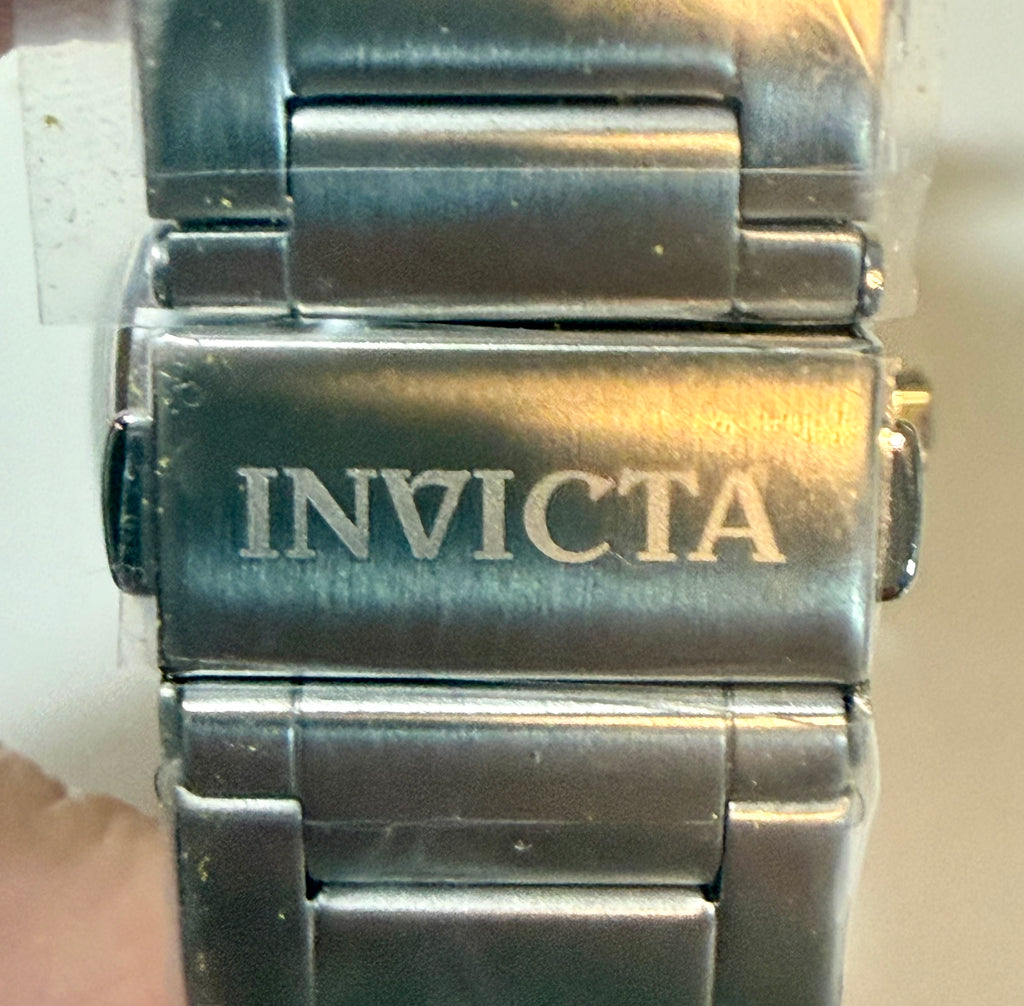 Close-up of a silver Invicta watch band on a neutral background