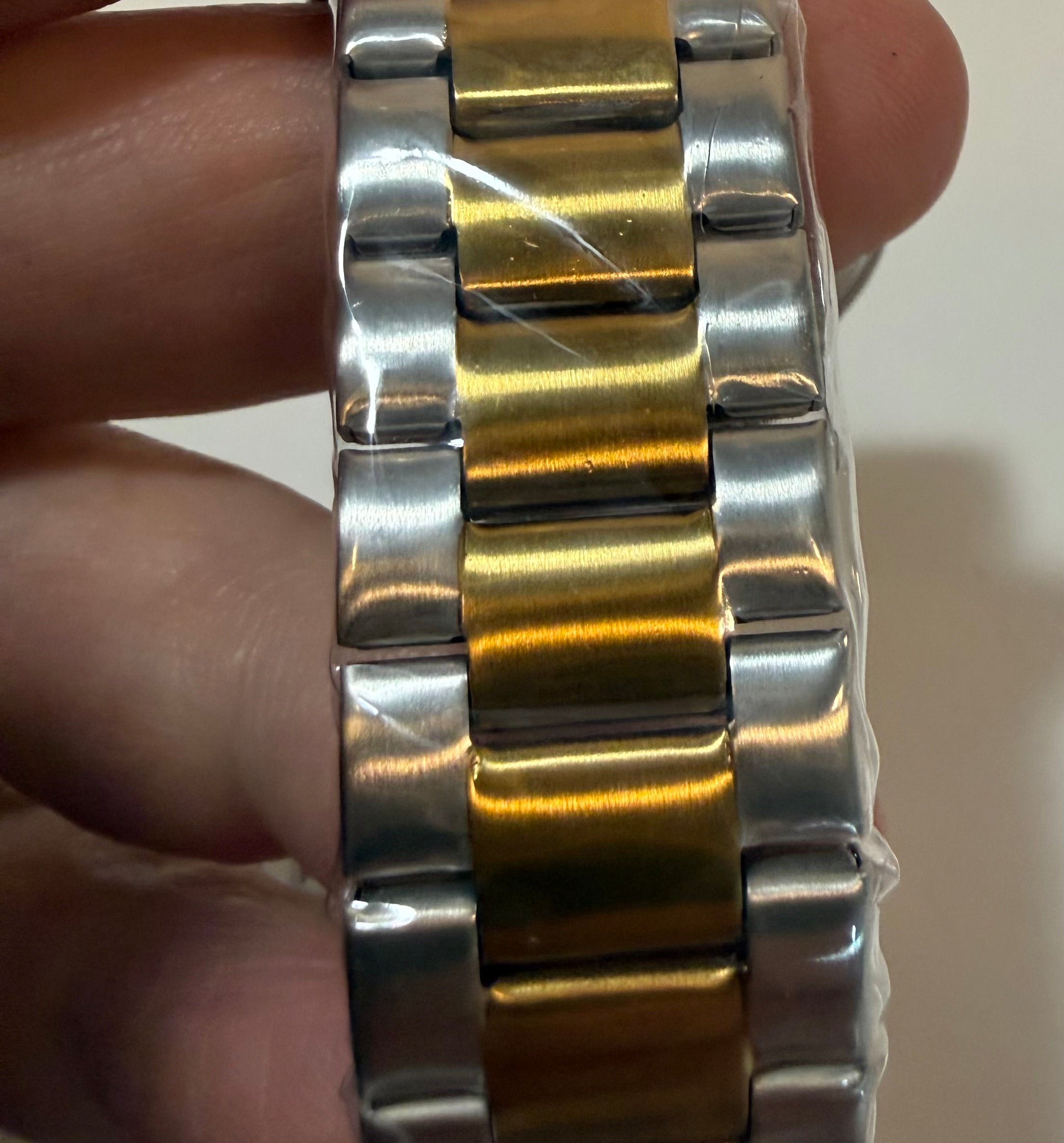 Close-up of a silver and gold watch band on a wrist.