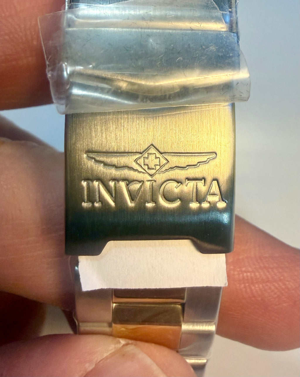 Close-up of a nvicta Speedway Monte Carlo watch buckle with 'Invicta' branding held between fingers.