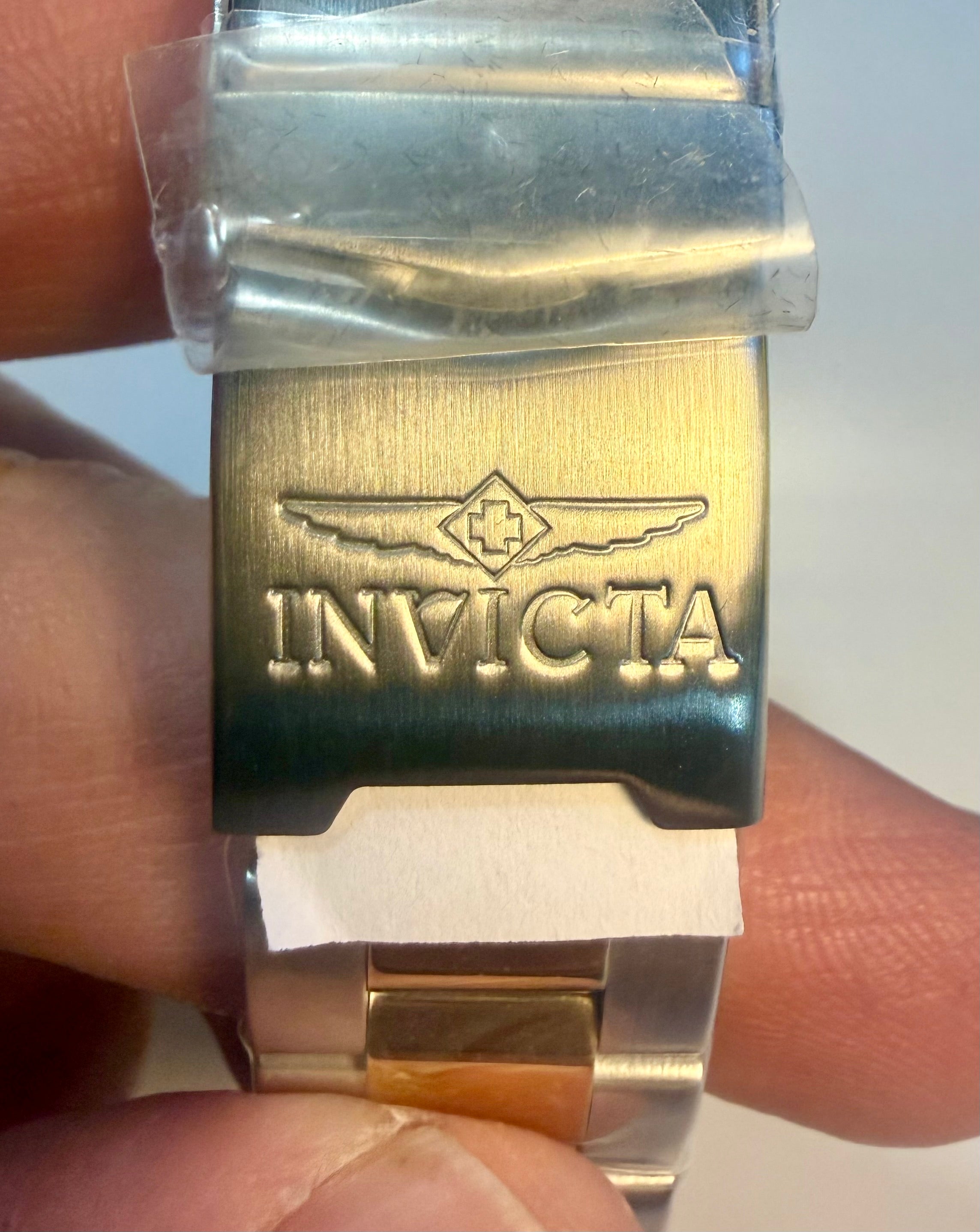 Close-up of a nvicta Speedway Monte Carlo watch buckle with 'Invicta' branding held between fingers.