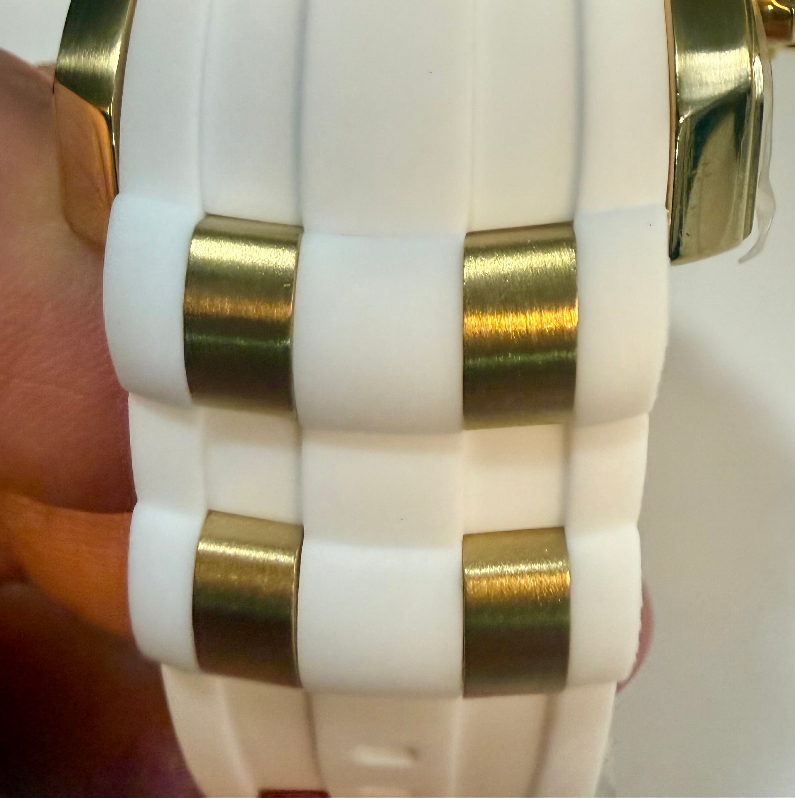 Close-up of a white and gold woven strap on a wrist.