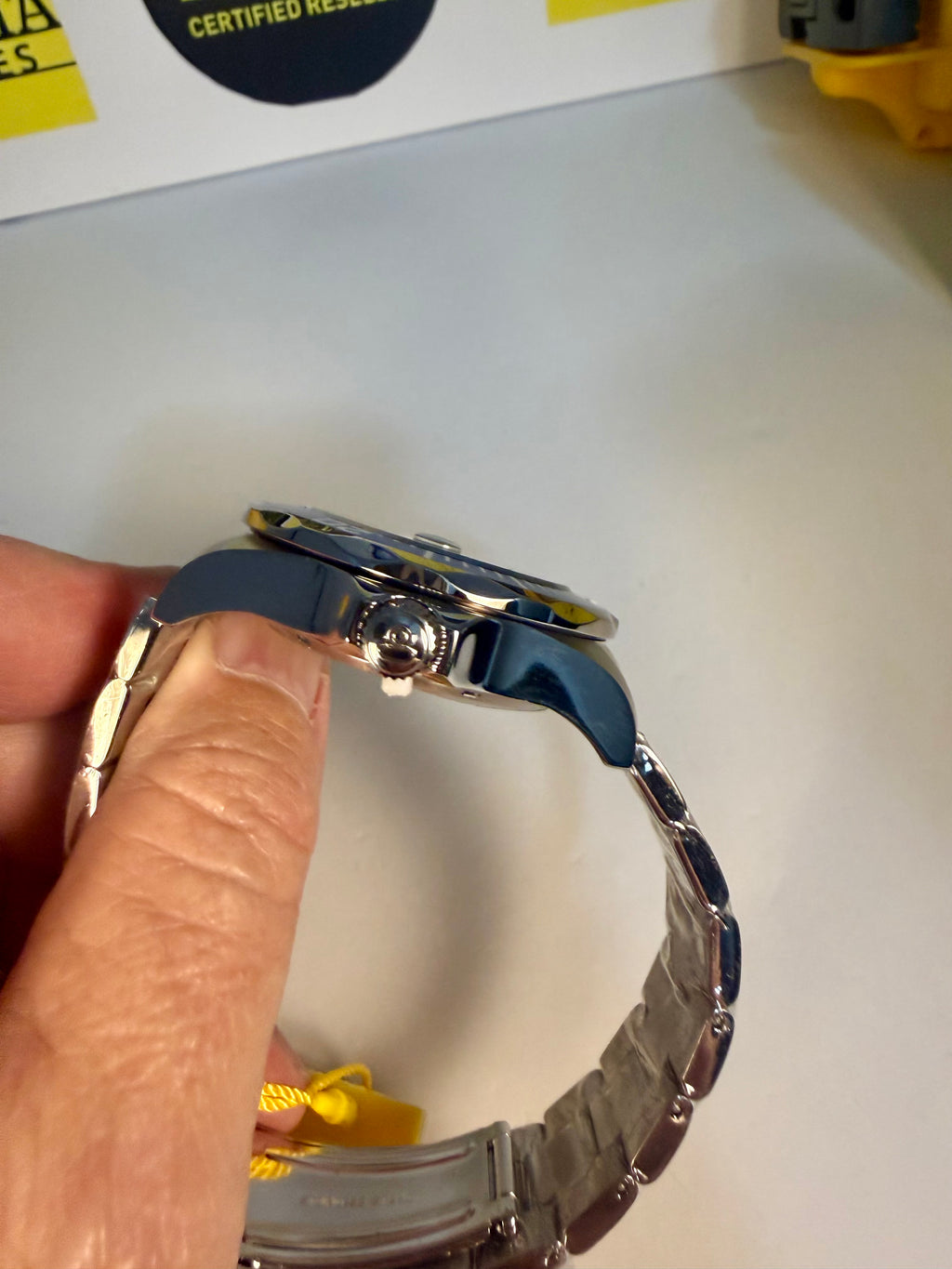 Close-up of a Invicta with a blue strap held by a hand on a white background.