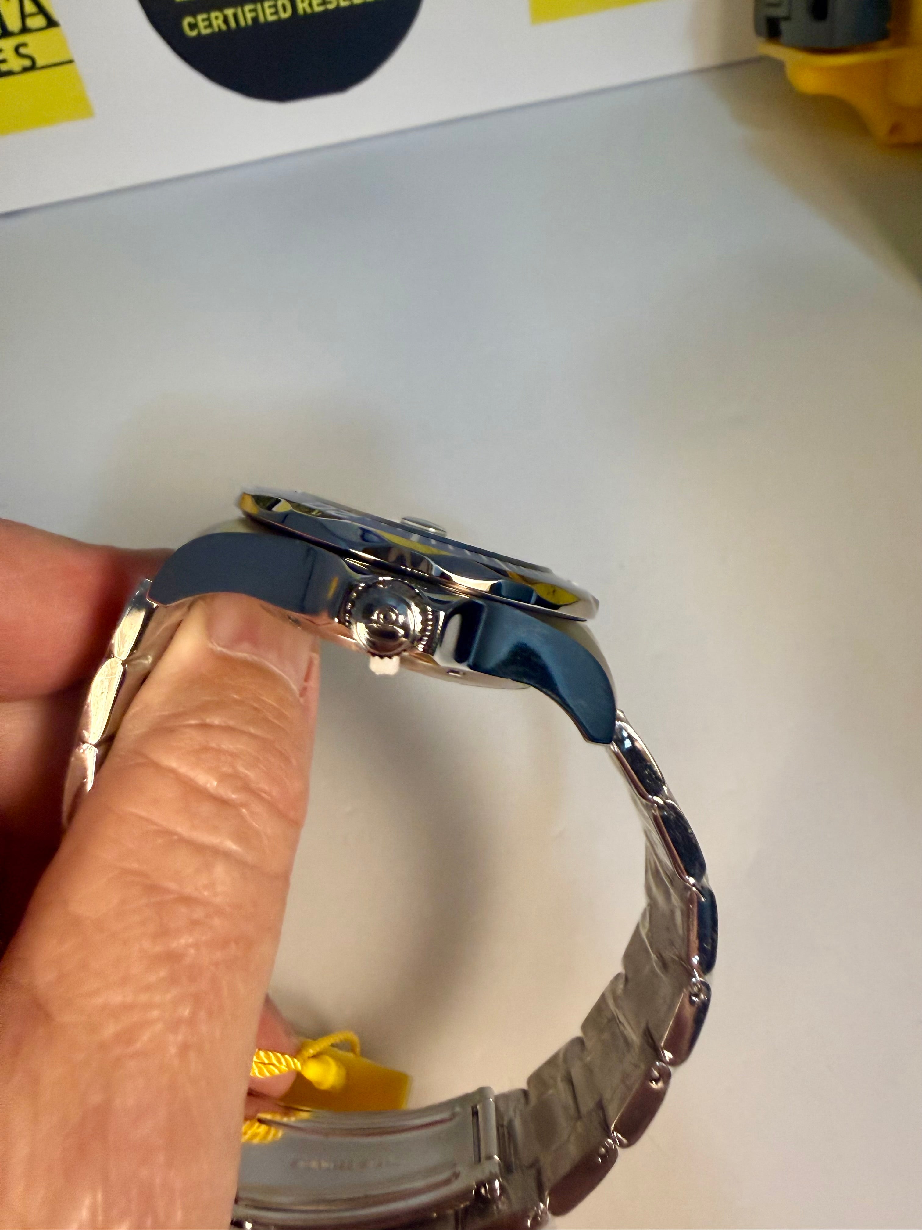 Close-up of a Invicta with a blue strap held by a hand on a white background.
