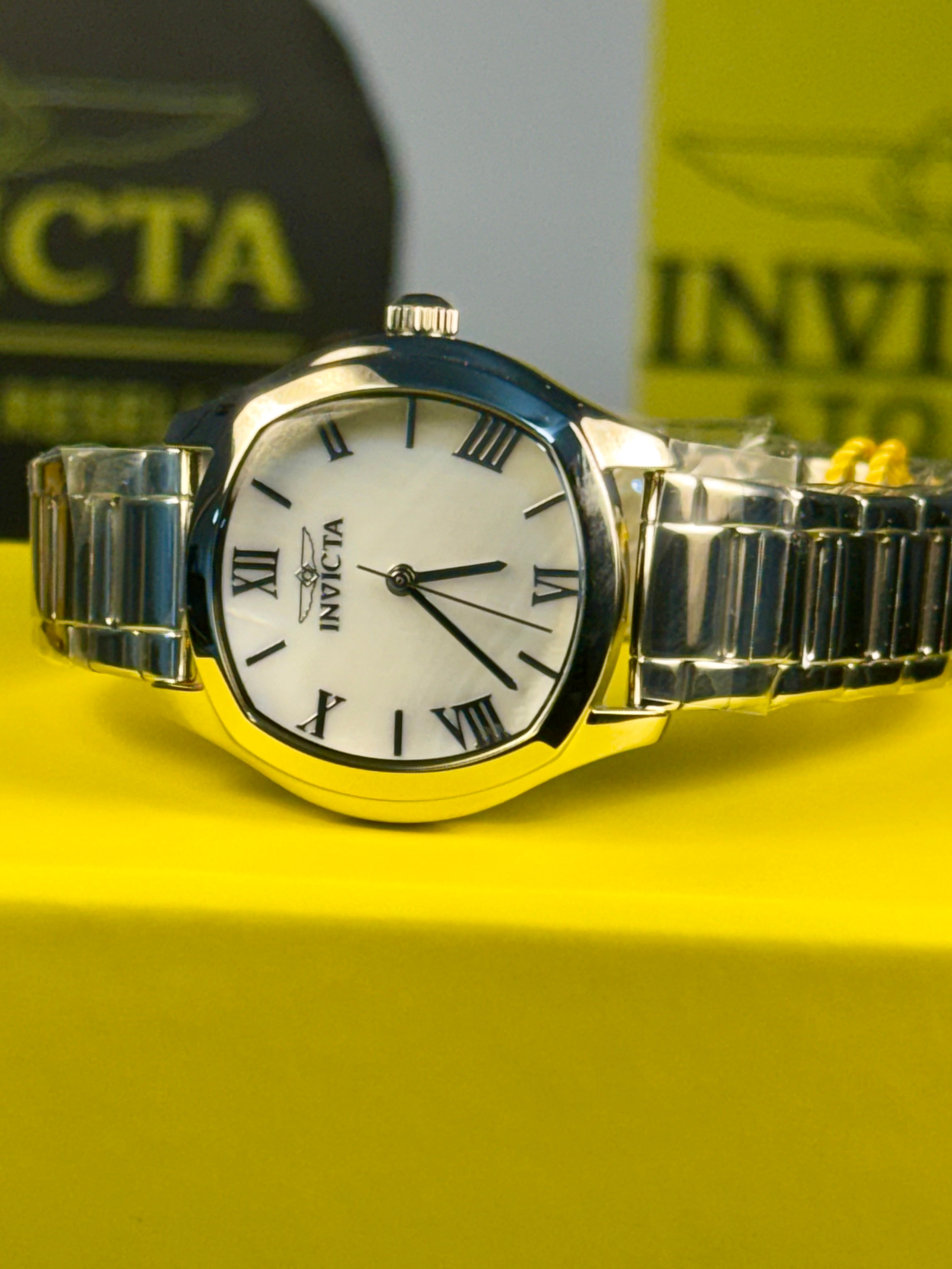 Invicta Ladies Wildflower Silver Invicta watch on a yellow surface with a blurred background