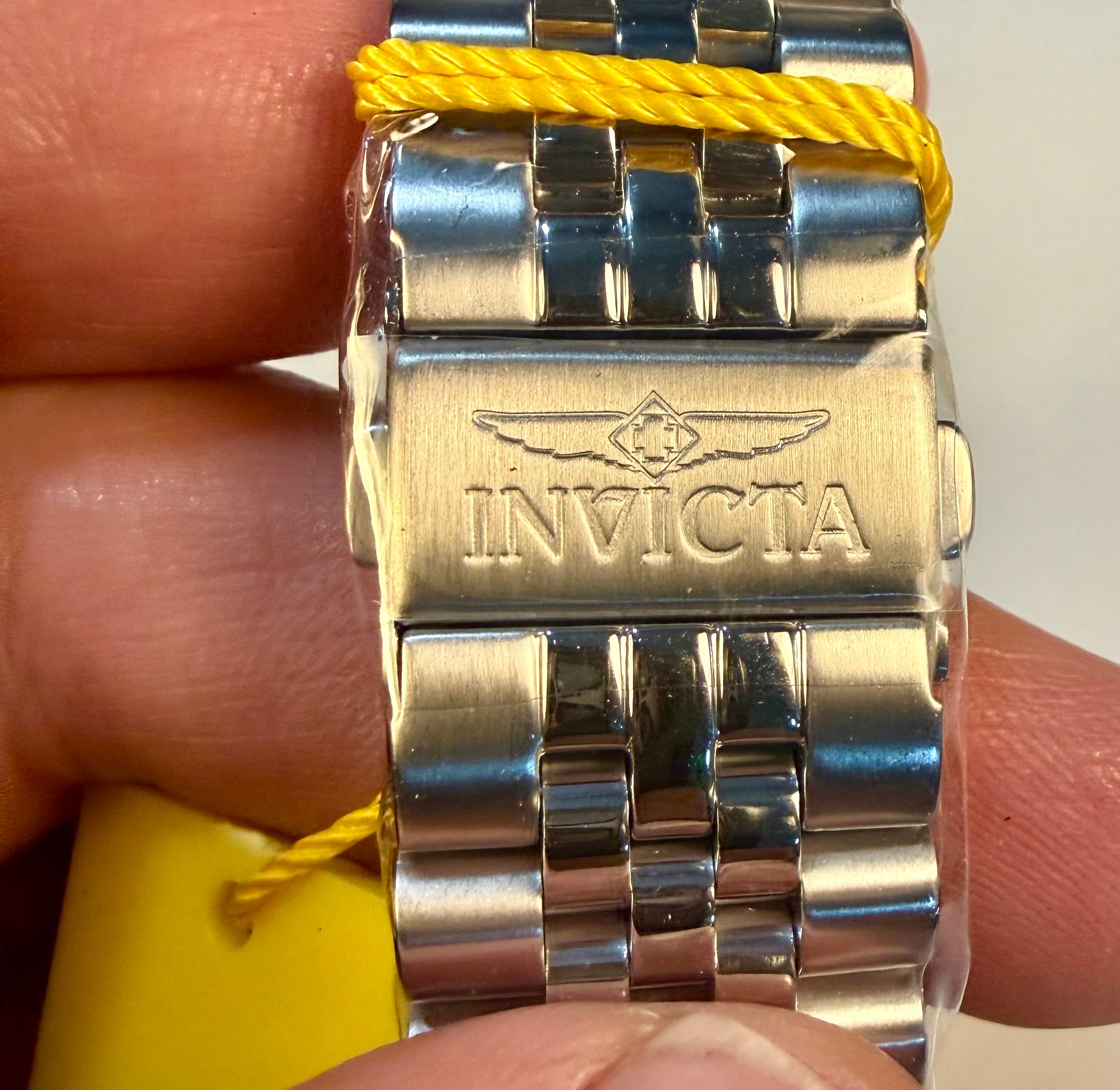 Invicta watch band on a wrist with a yellow strap