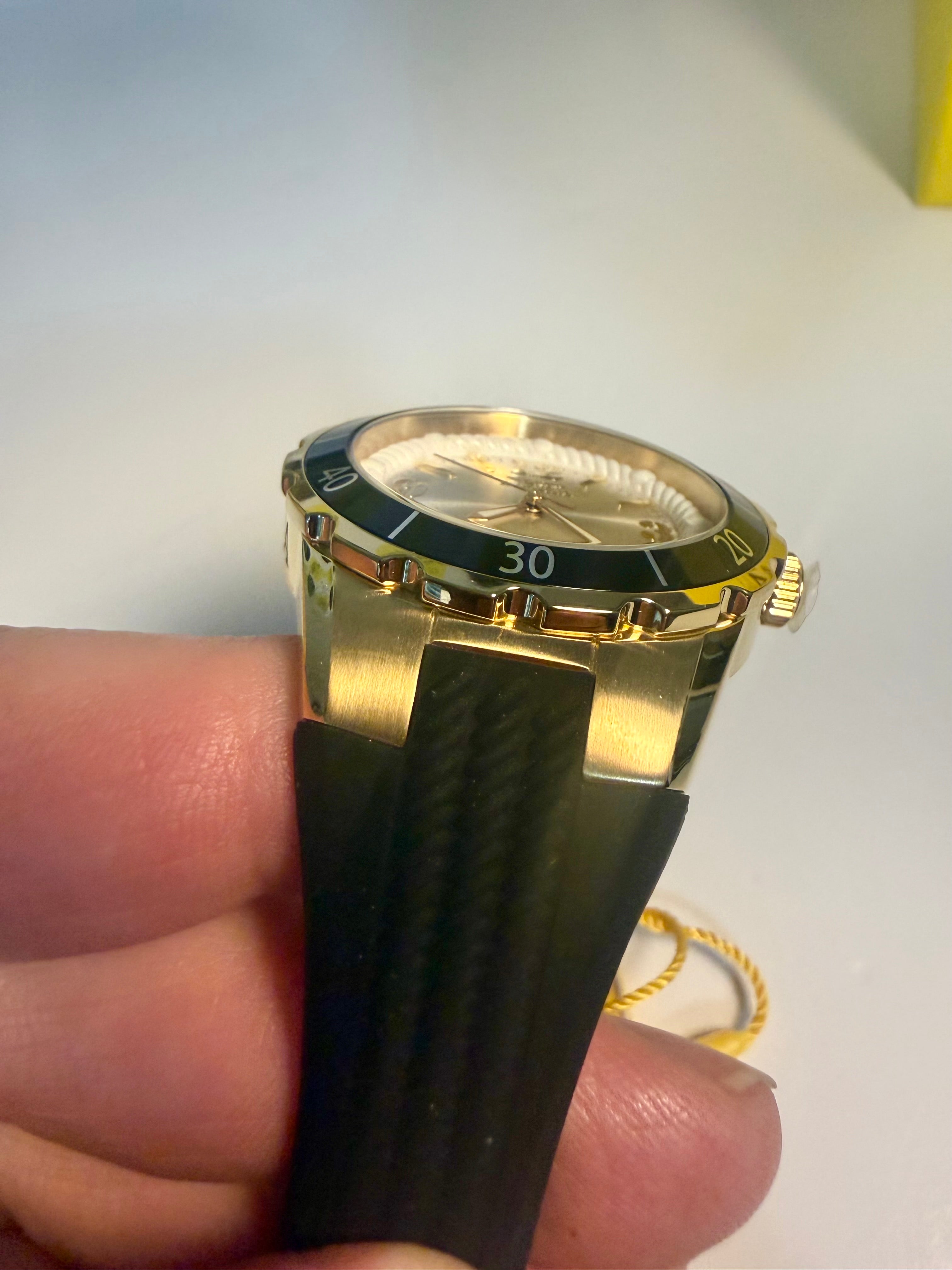 Invicta Ladies Angel Gold and black watch held in a hand with a plain background