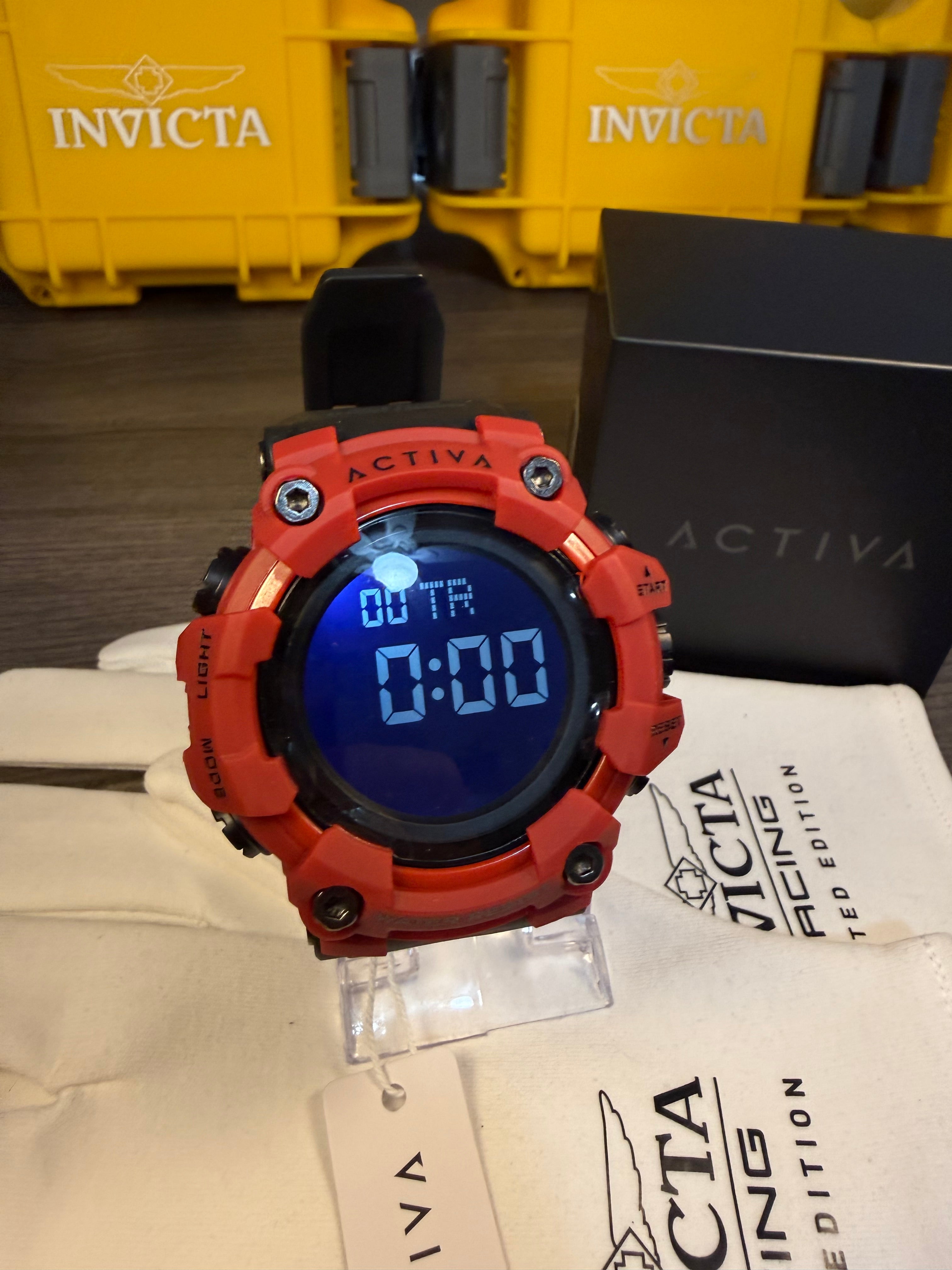 Red Activa digital watch with blue screen on a white background, next to Invicta packaging.