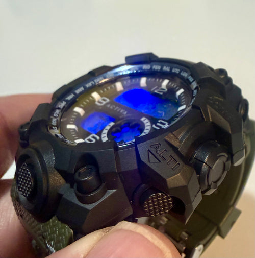 Activa Tactical X Black and green digital wristwatch held in a hand with a white background