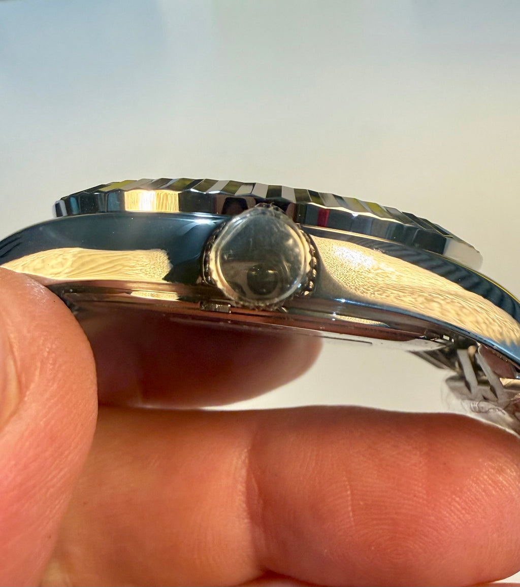 Close-up of a Mens Specialty Rowan 43mm between fingers against a light background