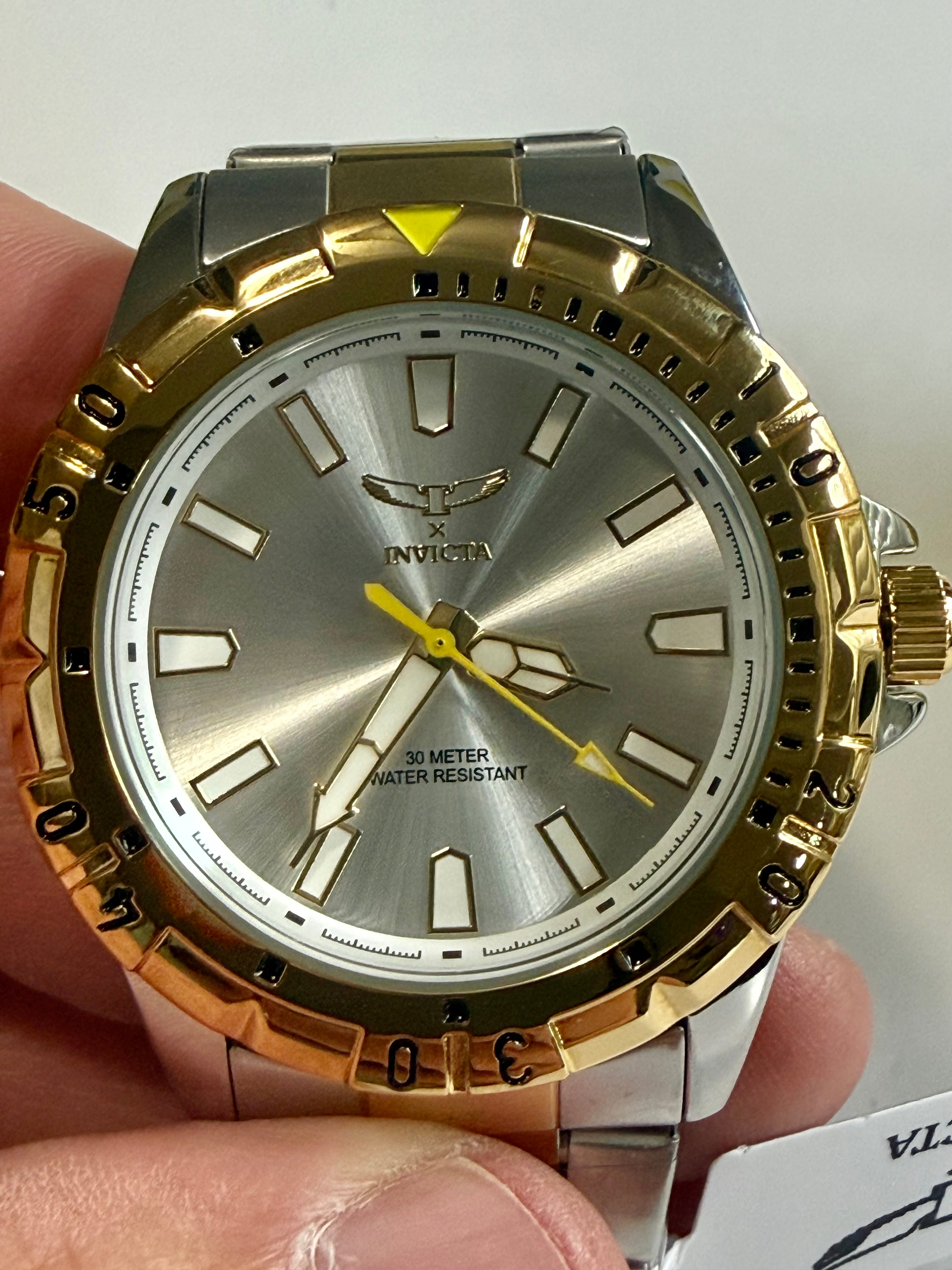 Invicta Specialty I Mens 42mm Gold and silver watch held by a hand with a white background