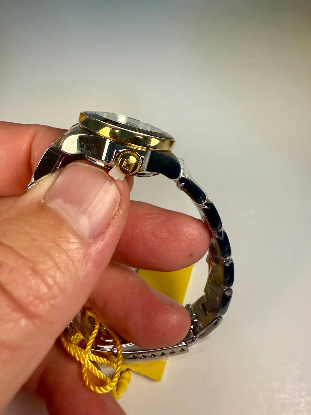 Hand holding a Ladies Invicta Pro Diver 24.5 mm watch with a gold case and black band on a white background