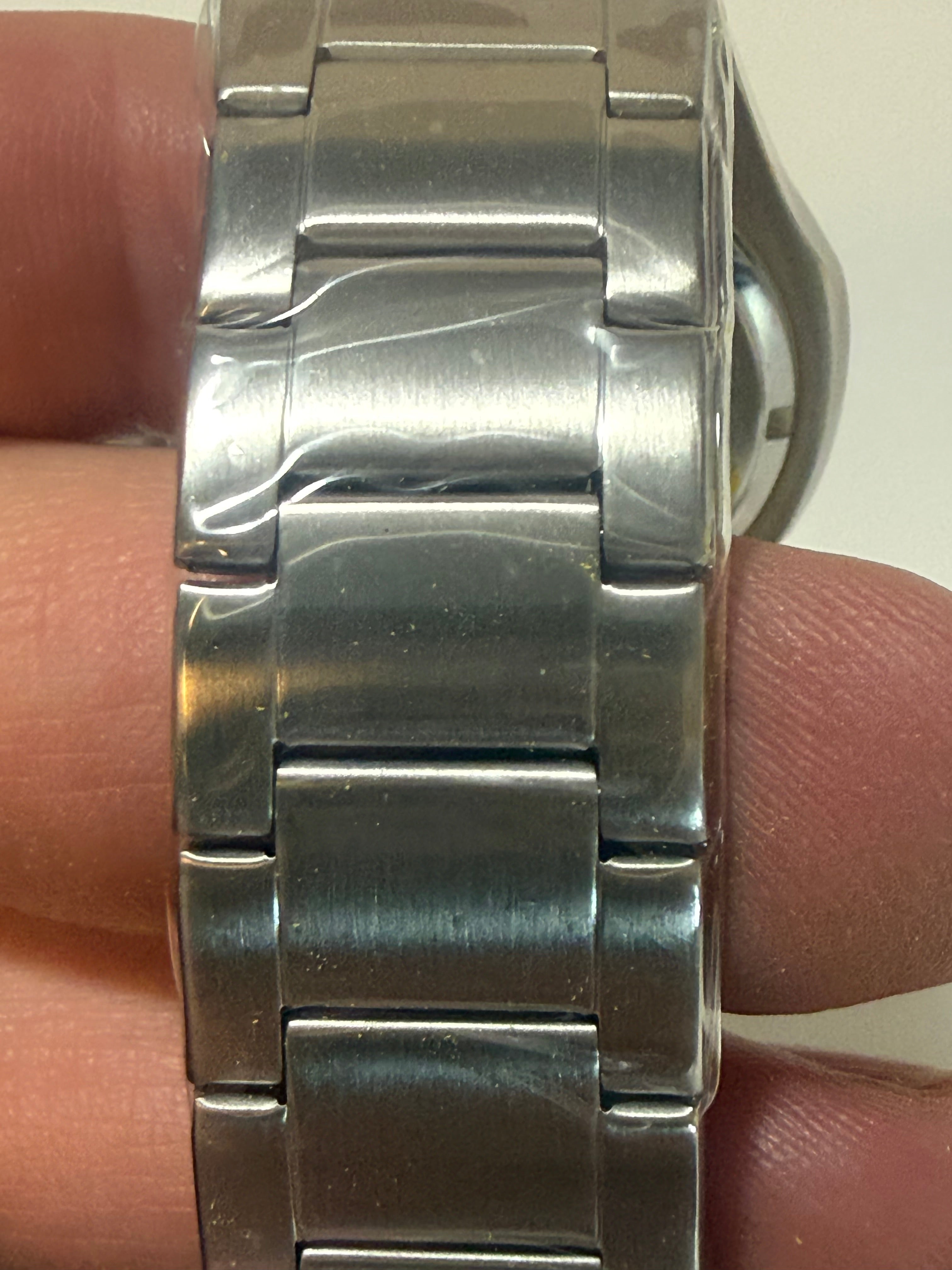Close-up of a silver metal watch band on a person's wrist.