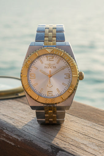 Invicta Ocean Voyage 38mm Pro Diver Gold and silver watch on a white surface with Invicta branding in the background.