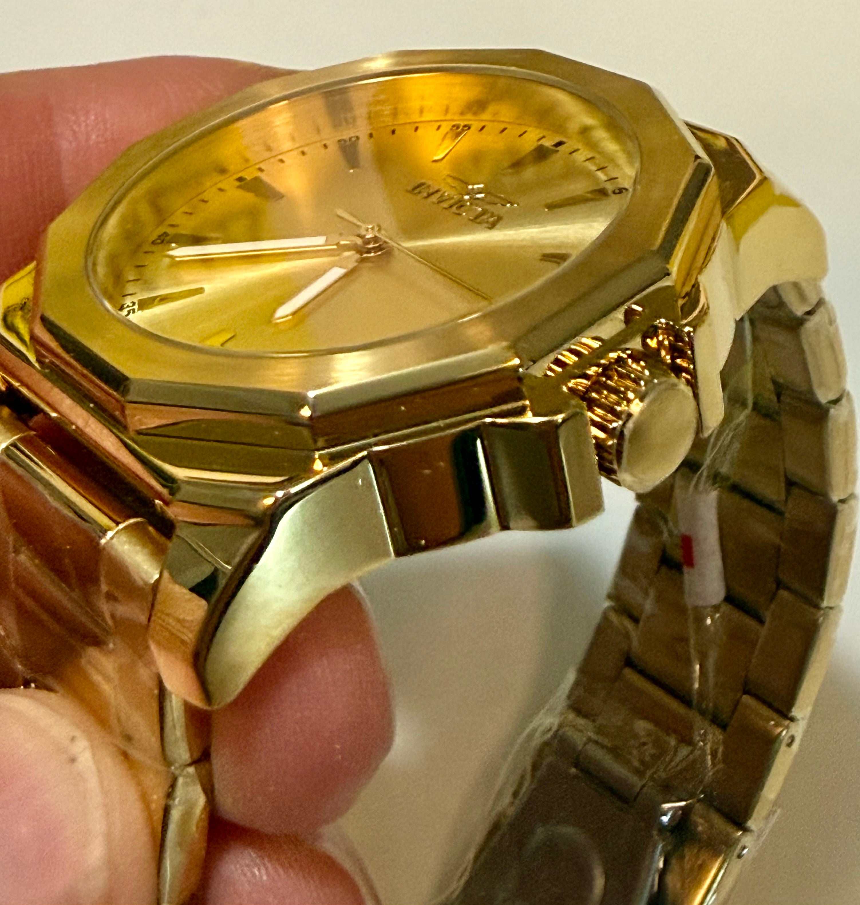 Invicta Speedway 46840 Gold Dial Gold Plated Steel 42mm Quartz Men's Watch held by a hand with a plain background