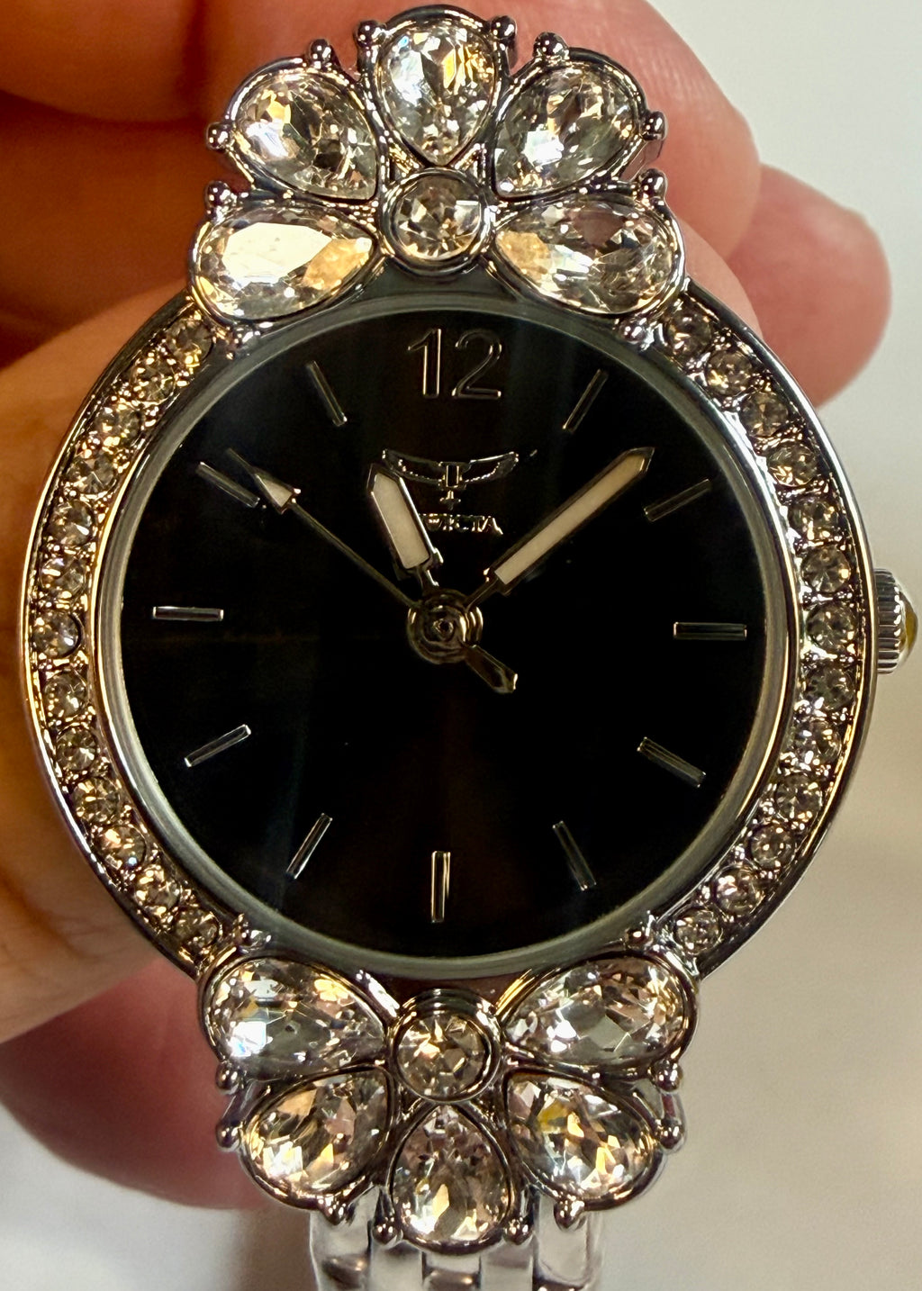 Invicta Ladies Wildflower 30mm Decorative watch with gemstones held by a hand on a white background