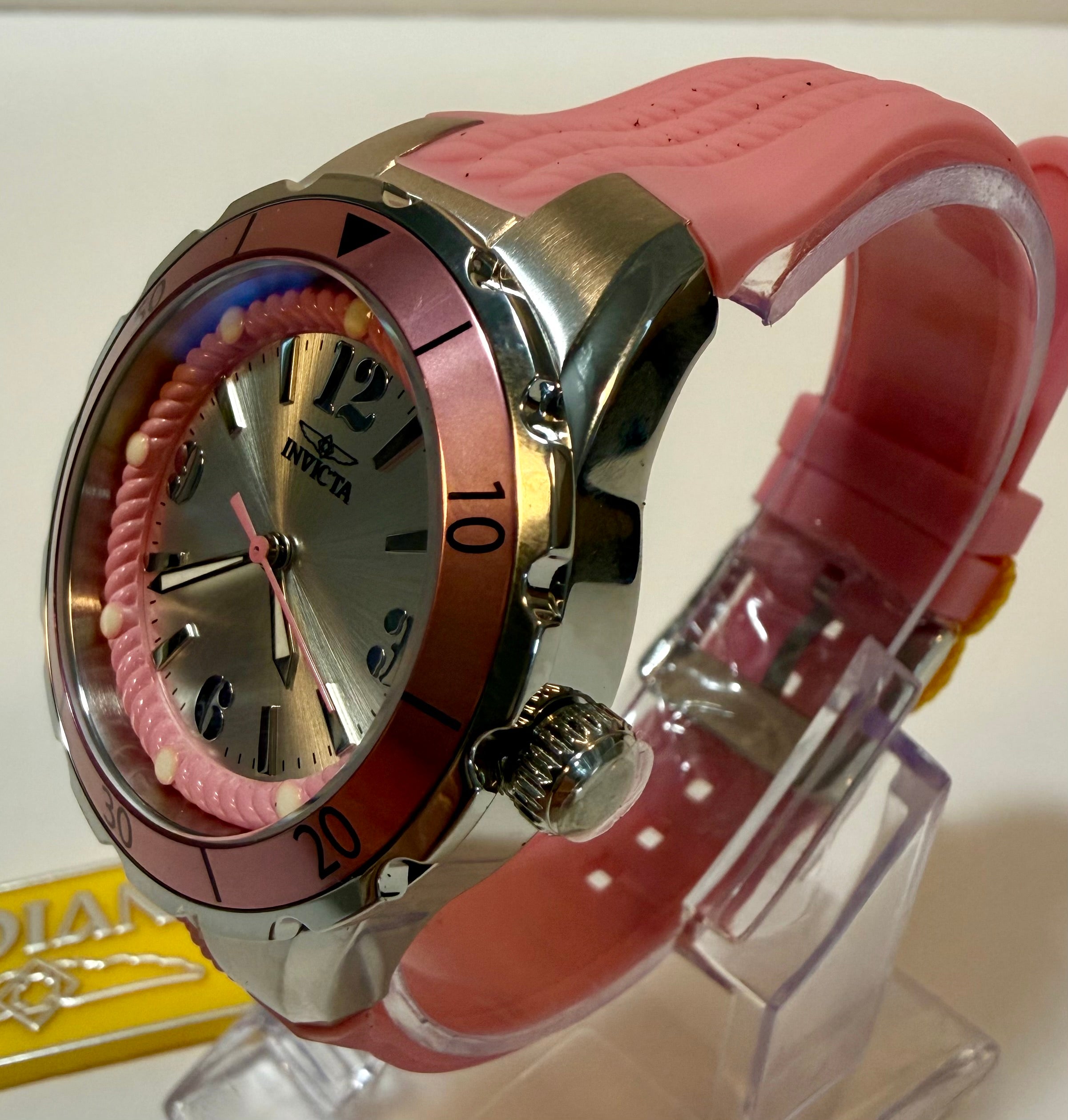 Pink watch with a clear stand on a white background