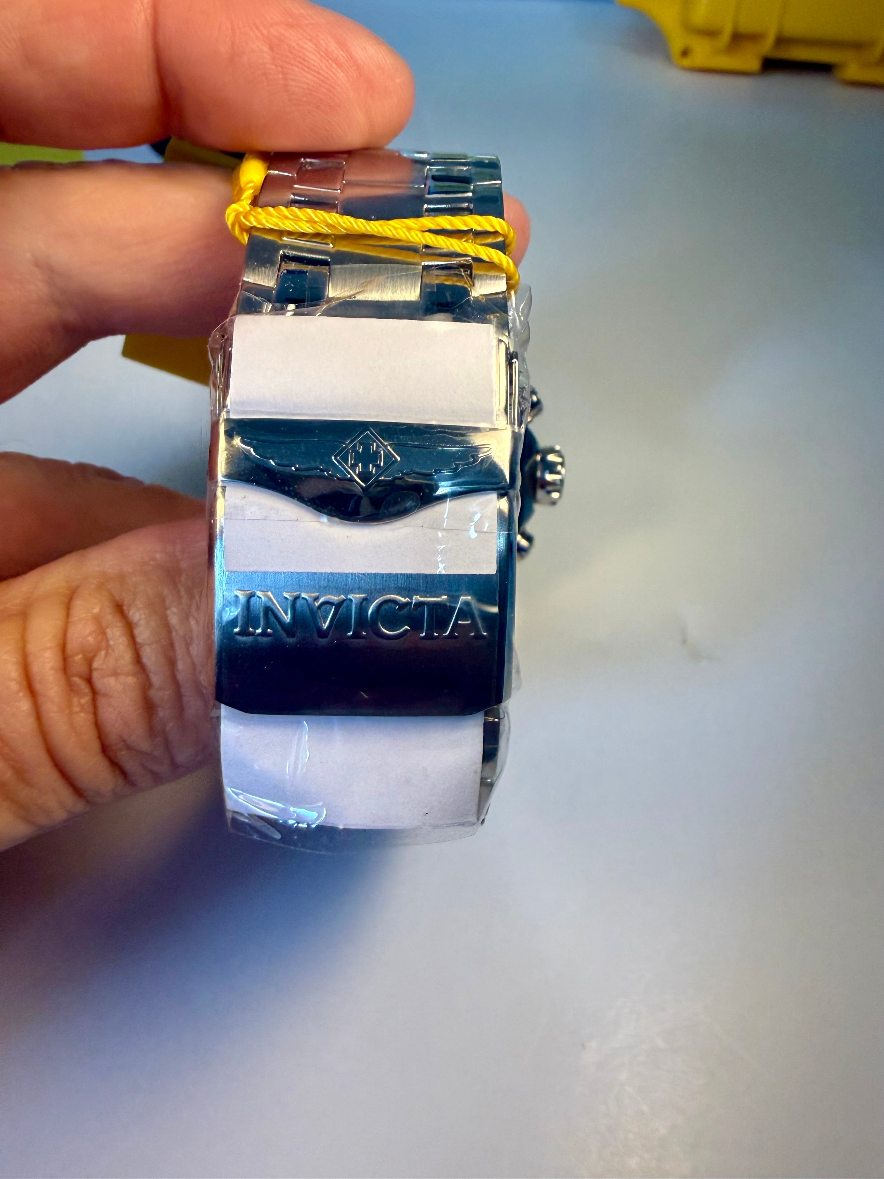 Invicta Pro Diver Scuba 48mmwatch with a yellow string held by a hand on a light gray background
