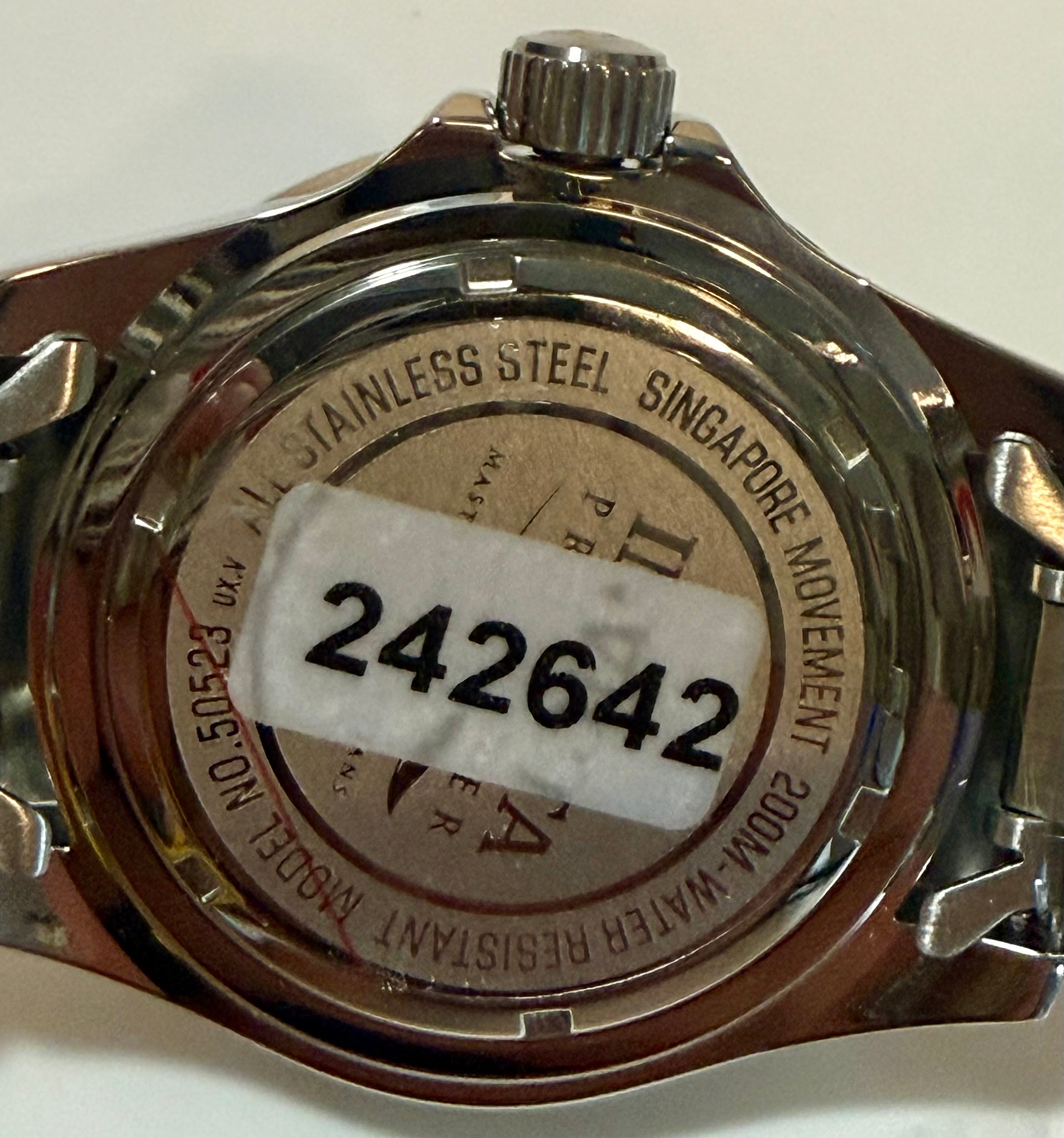 Back of a watch with 'Stainless Steel Singapore Movement' text and a visible serial number.