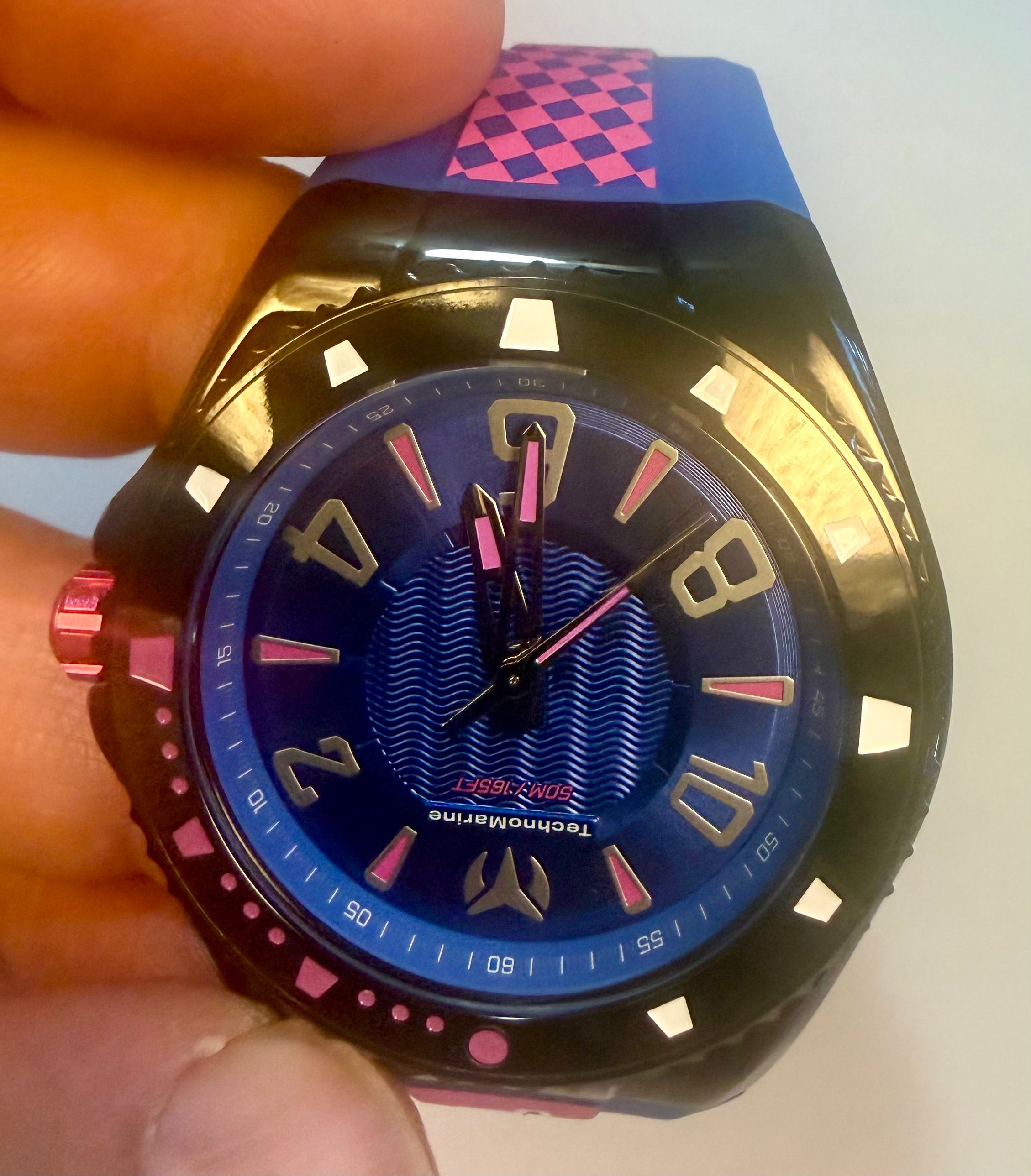 Close-up of a Techno Marine Racing Legends 44mm Wristwatch watch with a blue face and pink accents held by a hand.