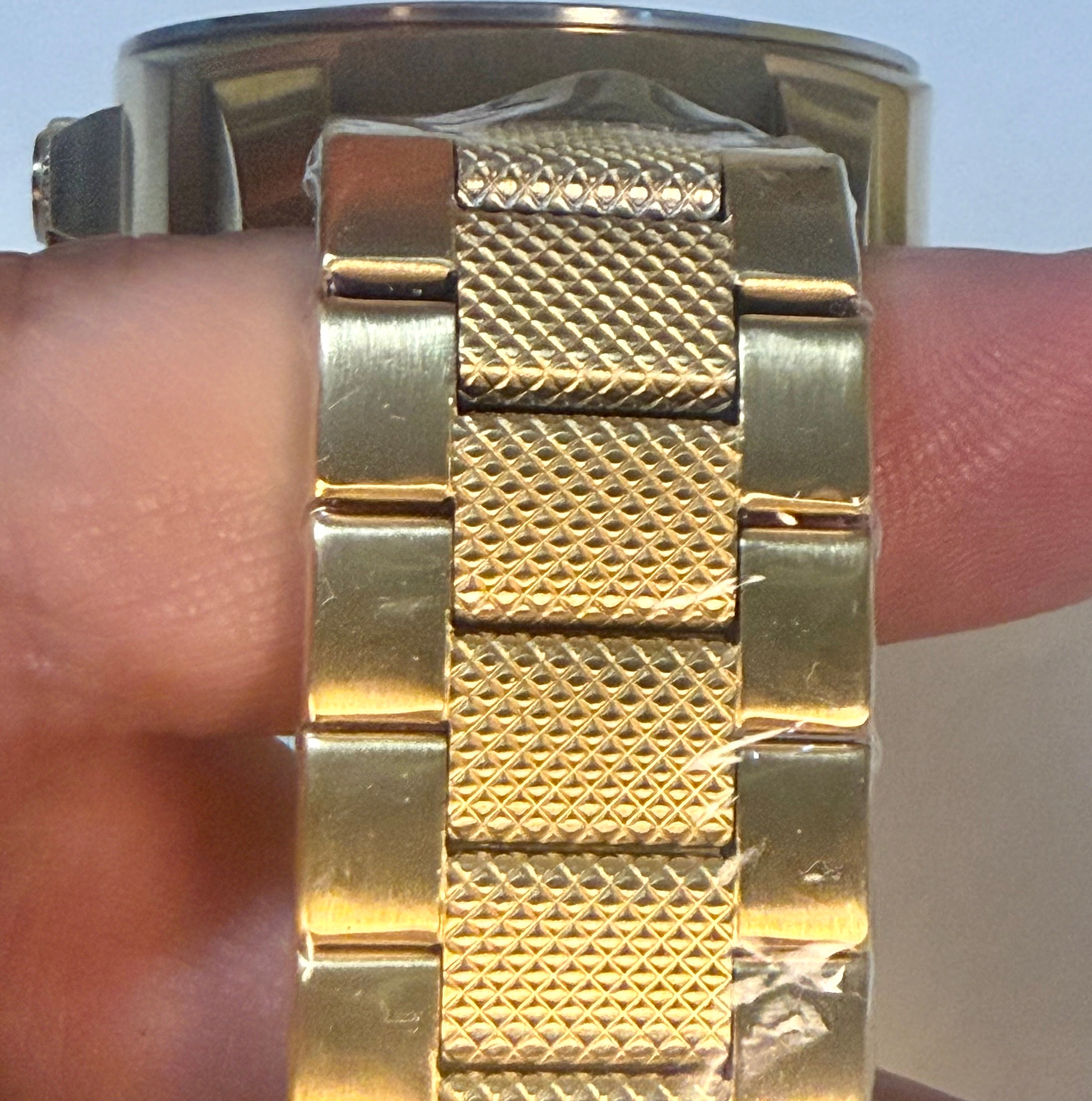 Invicta Speedway 48mm Gold watch with textured band on a wrist against a light background