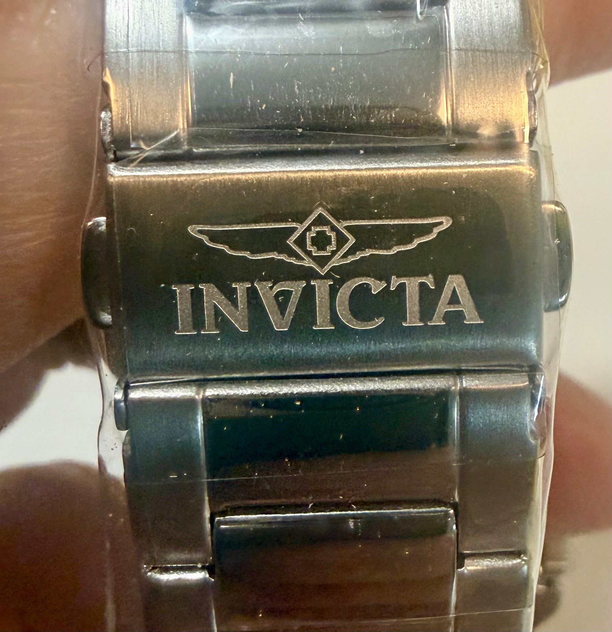 Close-up of a Invicta Speedway 42mm Mens Watch band with 'Invicta' branding on a wrist.