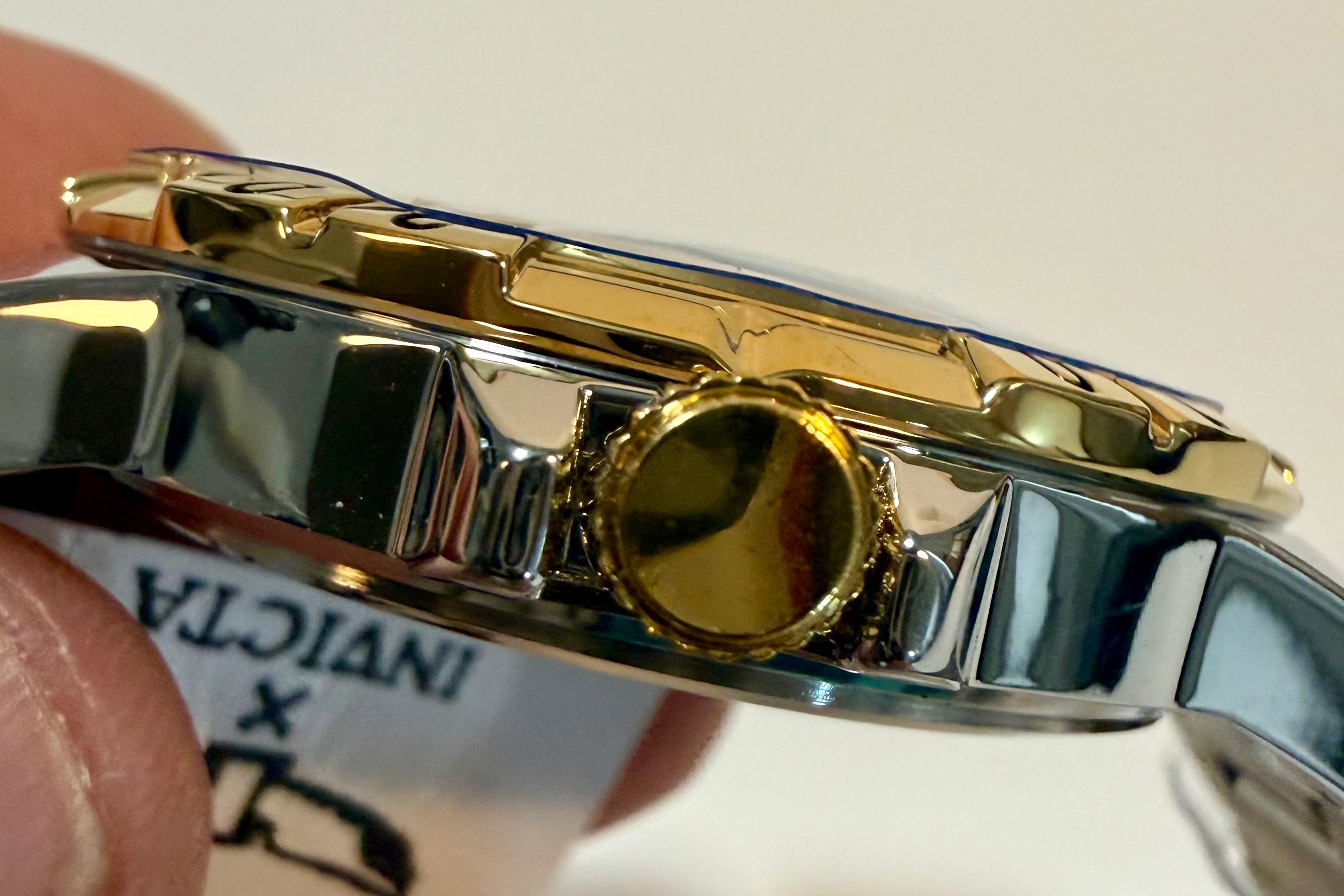 Close-up of a watch band with gold and silver finish, blurred background
