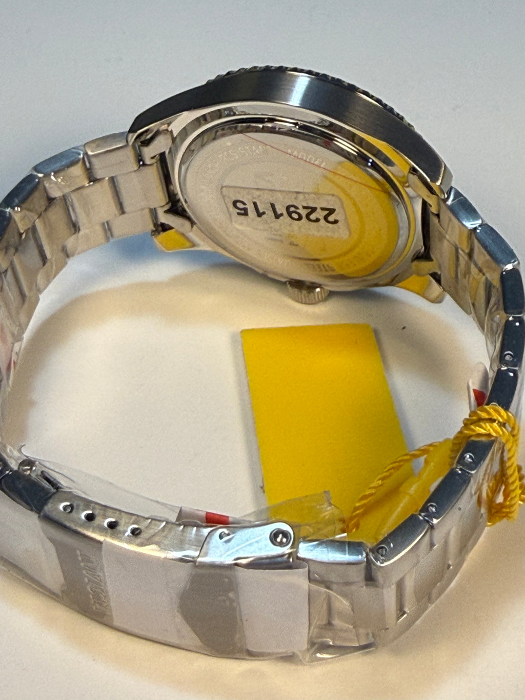 Close-up of a silver Invicta Mens Pro Diver watch with a yellow label on a white background