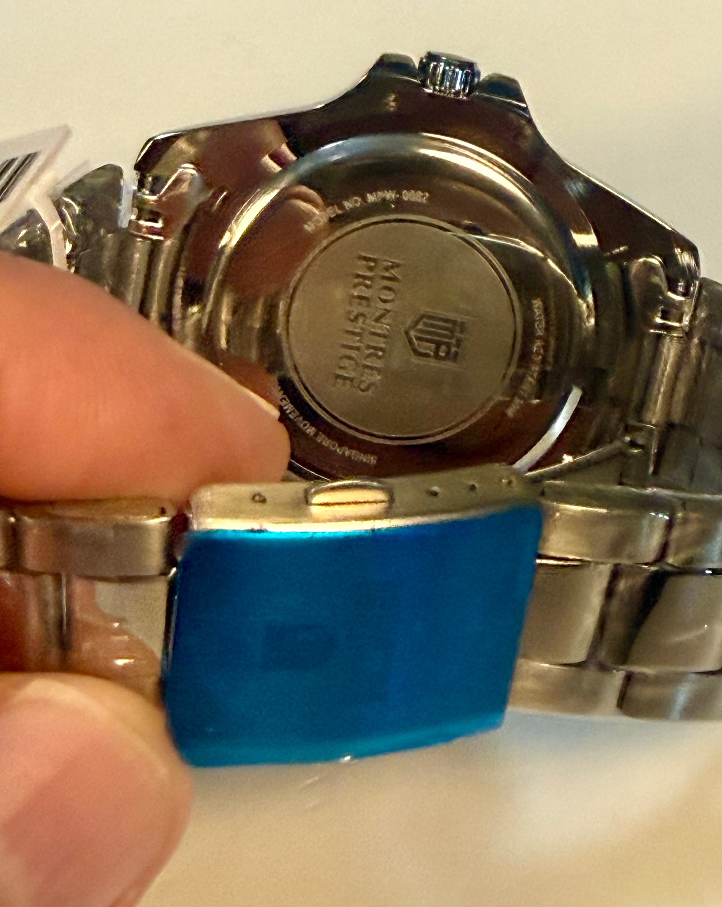 Close-up of a Montres Prestige 42mm Mens Pro Diver  watch with a blue tool on a white background