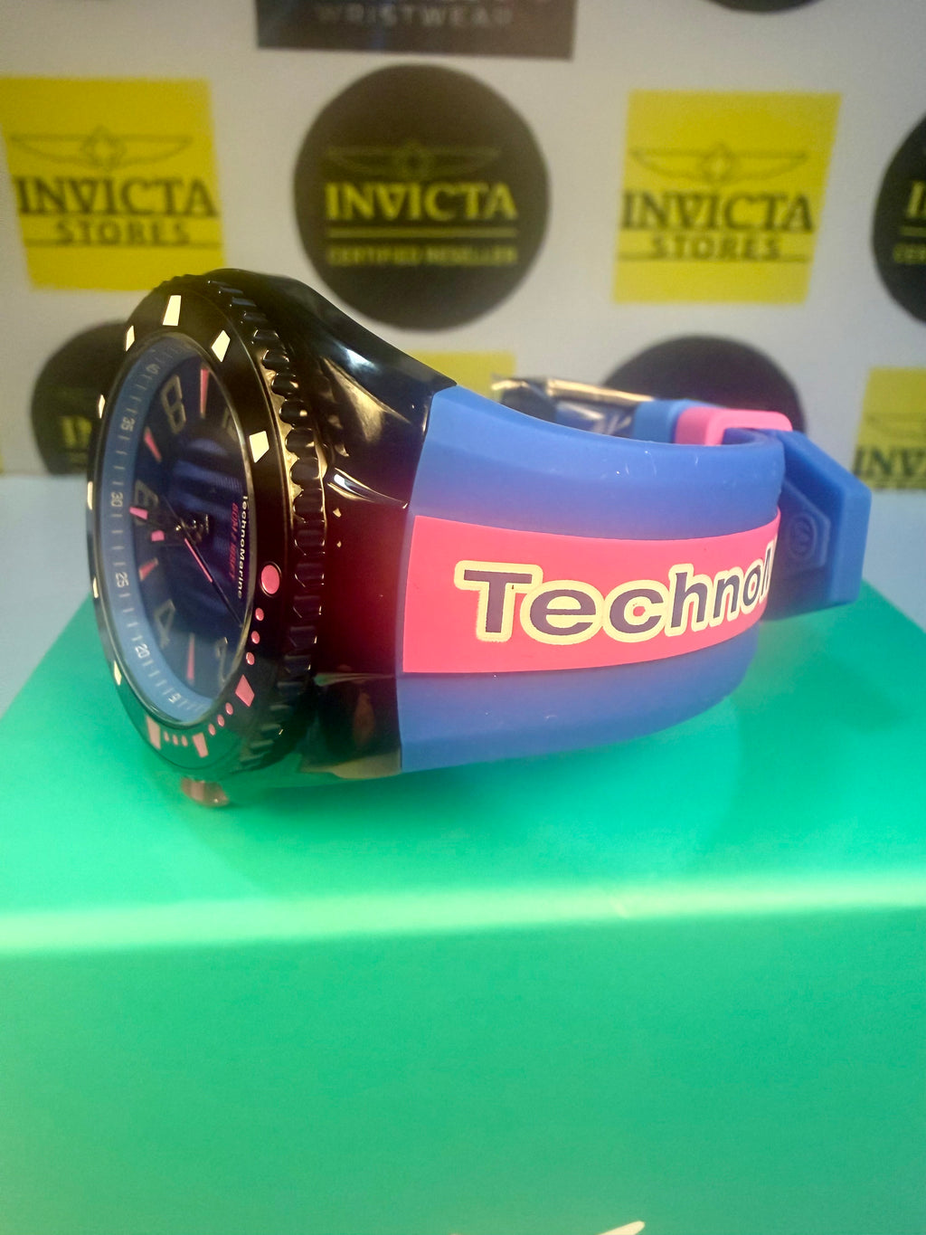 Techno Marine Racing Legends 44mm Wristwatch  Watch with a colorful strap labeled 'Techno' on a green surface with Invicta branding in the background.