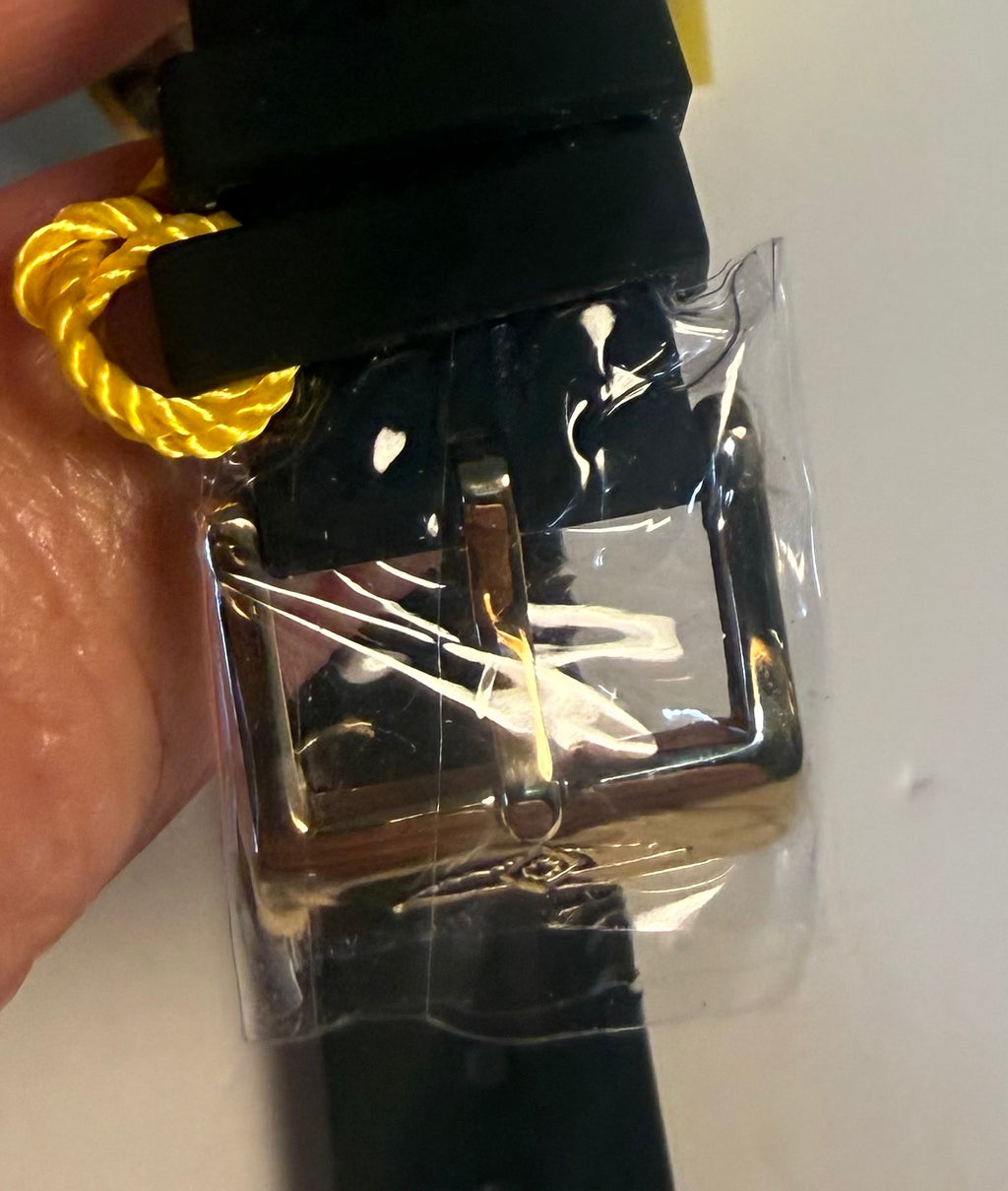 Invicta Ladies Angel  Black belt with gold buckle held by a hand on a white background
