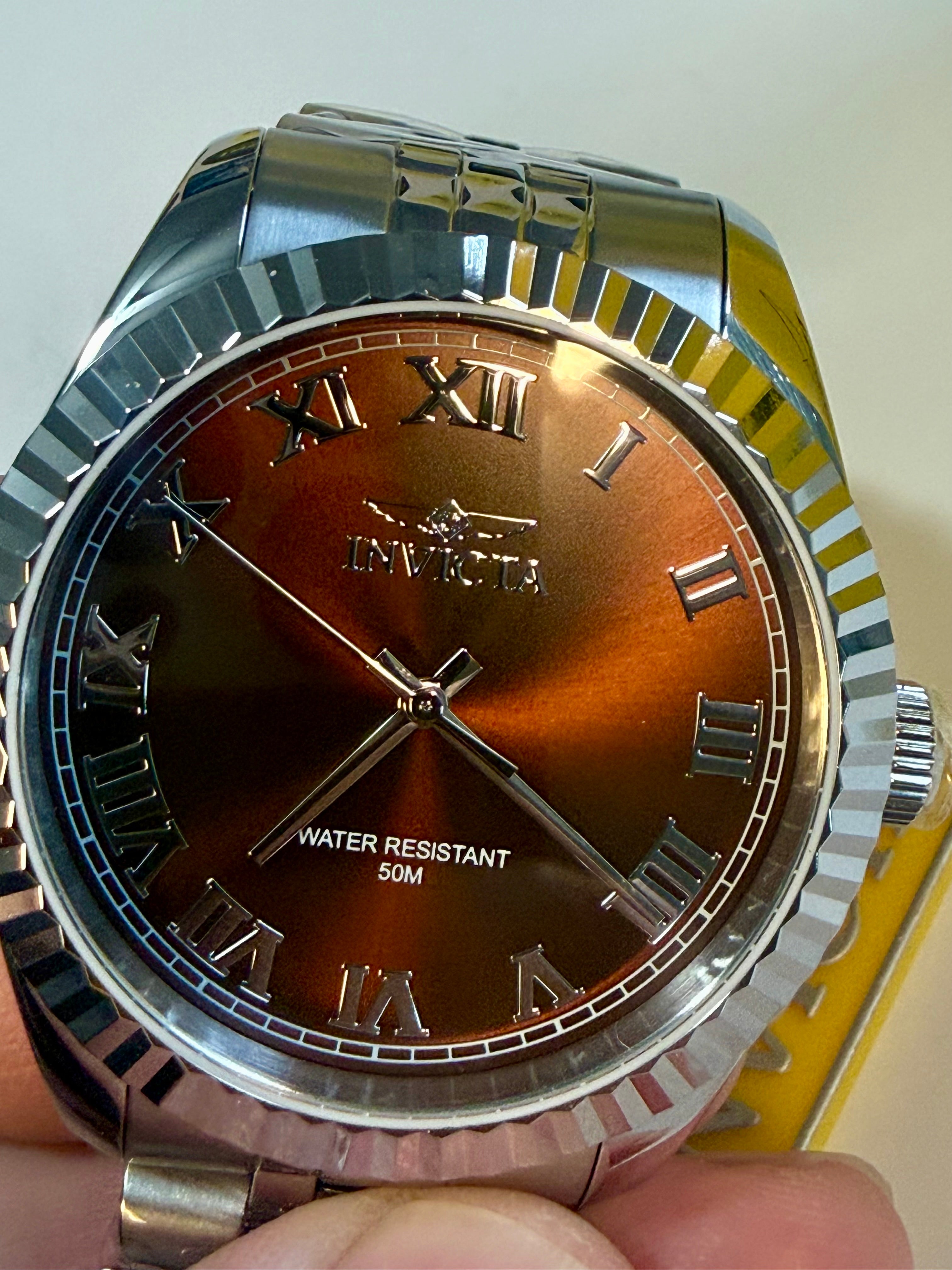 Invicta Specialty Windsor 43mm with brown face held by a hand against a neutral background