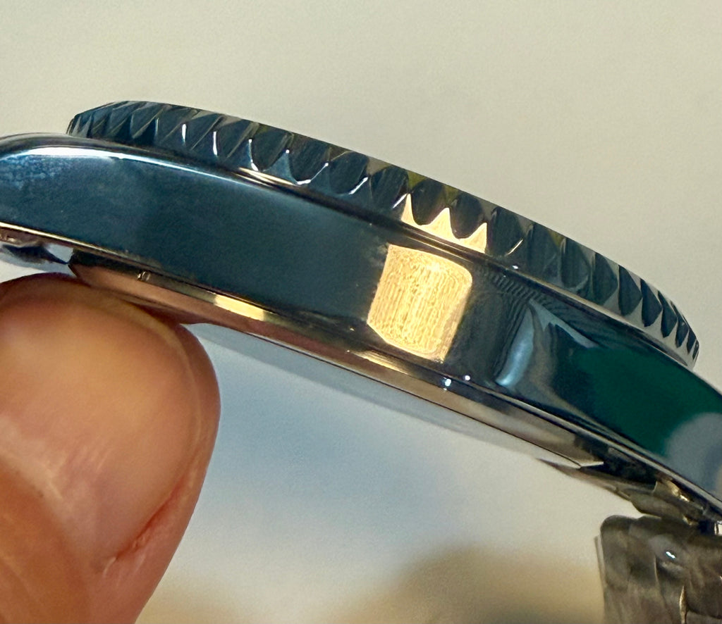 Close-up of a Montres Prestige 42mm Mens Pro Diver watch case with a brand logo, held by a hand against a neutral background.