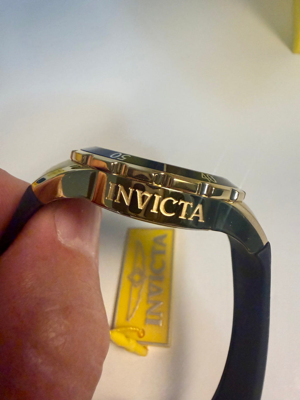 Invicta Ladies Angel  watch band with gold clasp held by a hand, Invicta logo visible on a white background.