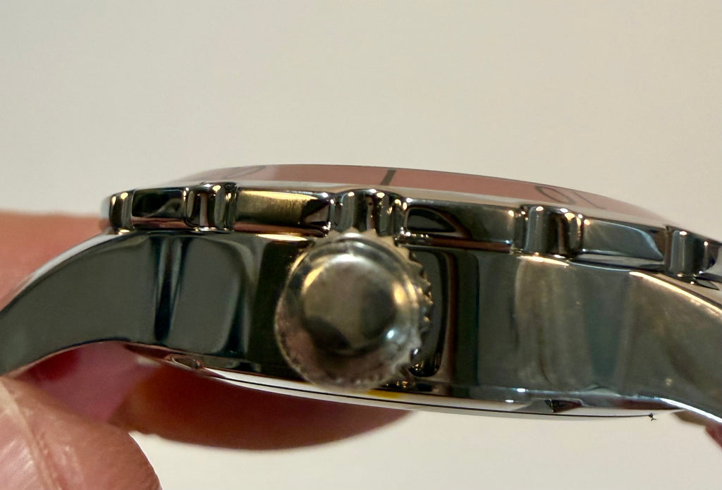 Close-up of a silver watch band with a blurred background