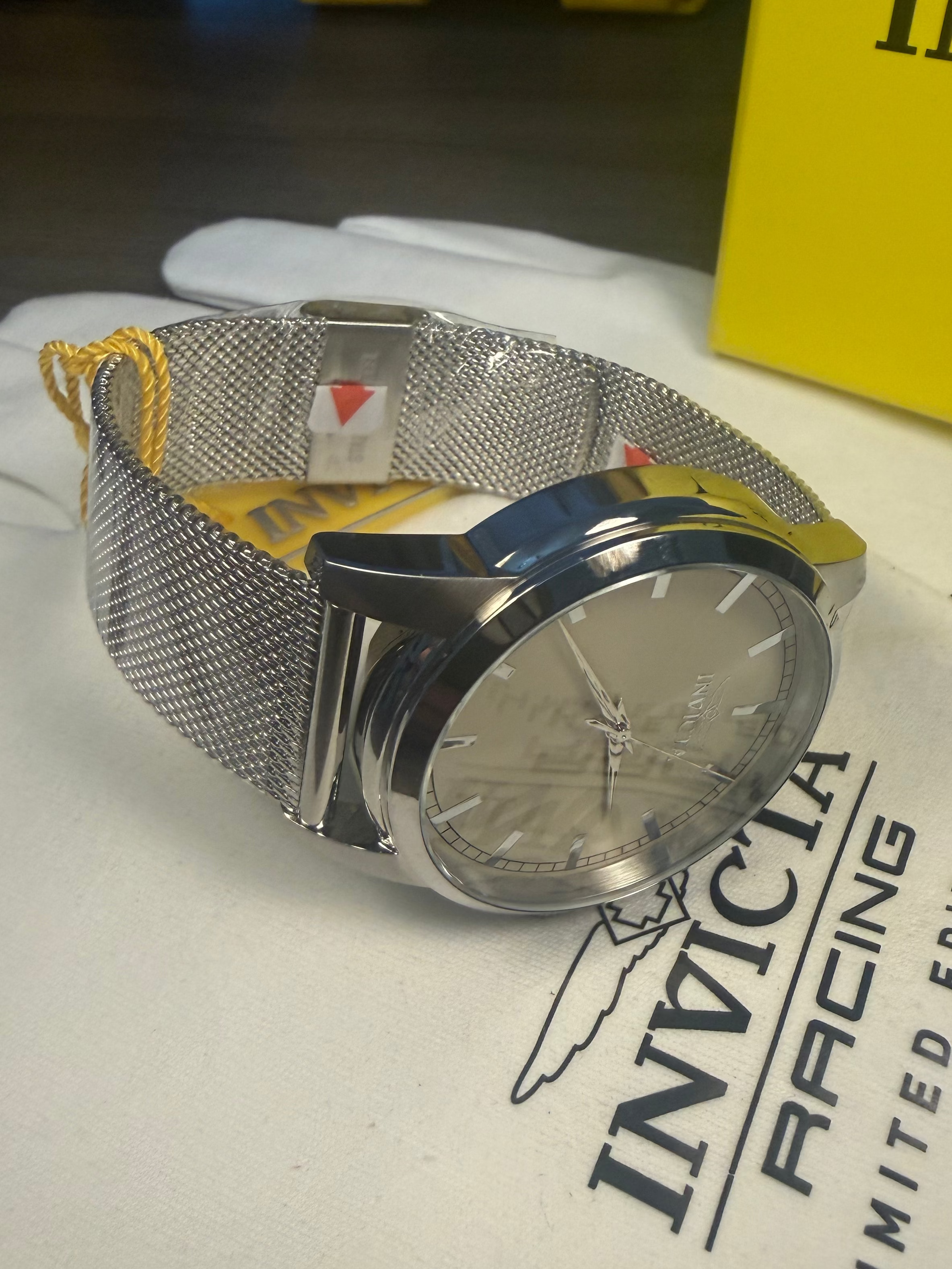 Invicta Mens Celestial Silver watch with mesh band on a white surface with 'Invicta Racing' branding.